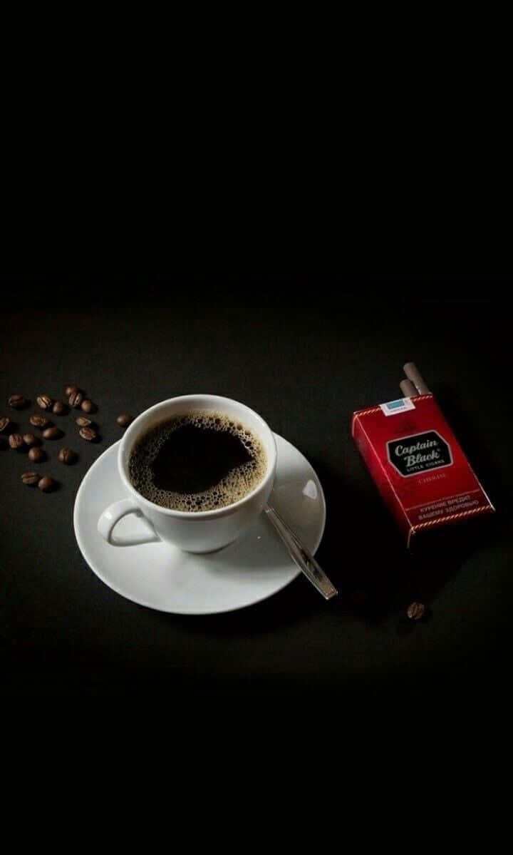 Black Coffee 桌布 壁紙 — 純黑背景凸顯白色咖啡杯、湯匙、散落的咖啡豆，以及旁邊的紅色香煙包。