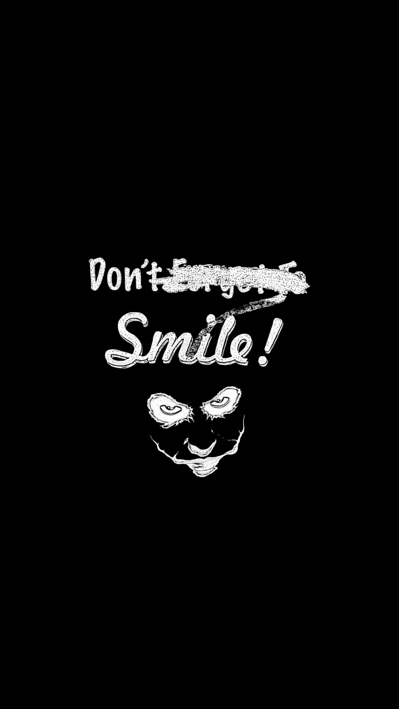 Joker Quotes 桌布 壁紙 — 純黑色背景上，白色粉筆風格文字寫著「Don't Forget to Smile!」，上方有一個眼睛發光的詭異笑臉。