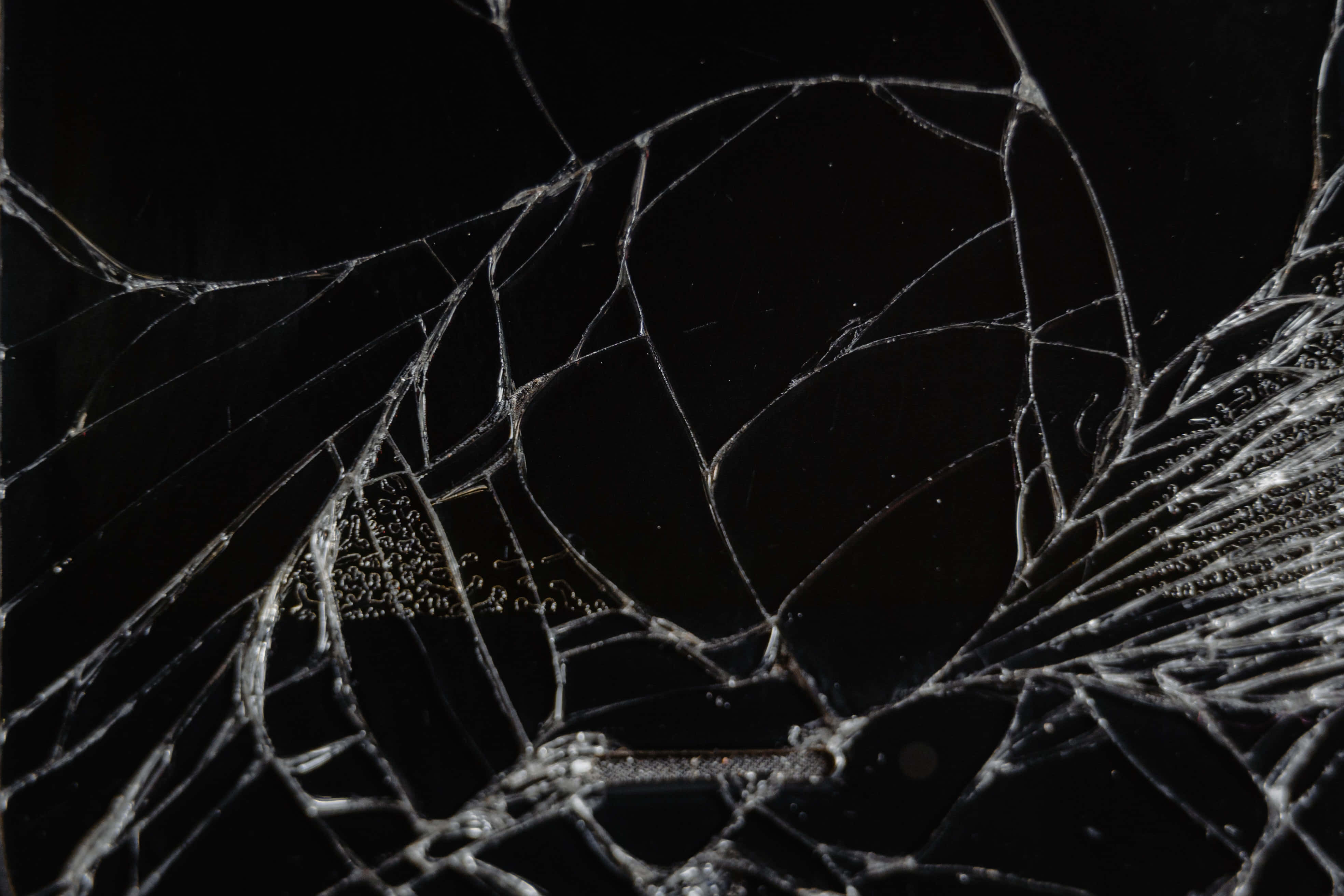 Broken Glass 桌布 壁紙 — 純黑色背景上帶有複雜裂紋的碎玻璃特寫。