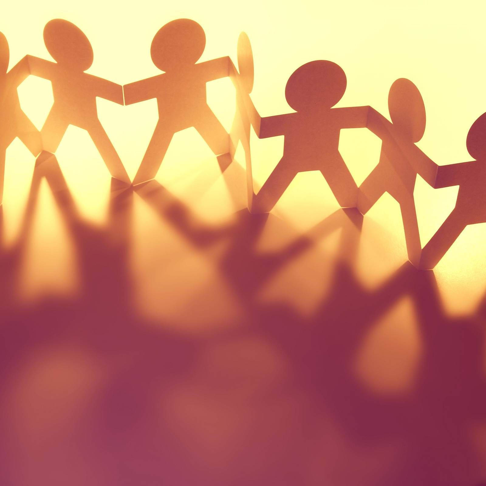 group 桌布 壁紙 — 紙剪影人物手牽手形成溫暖發光的鏈條，背景為柔和漸變色。