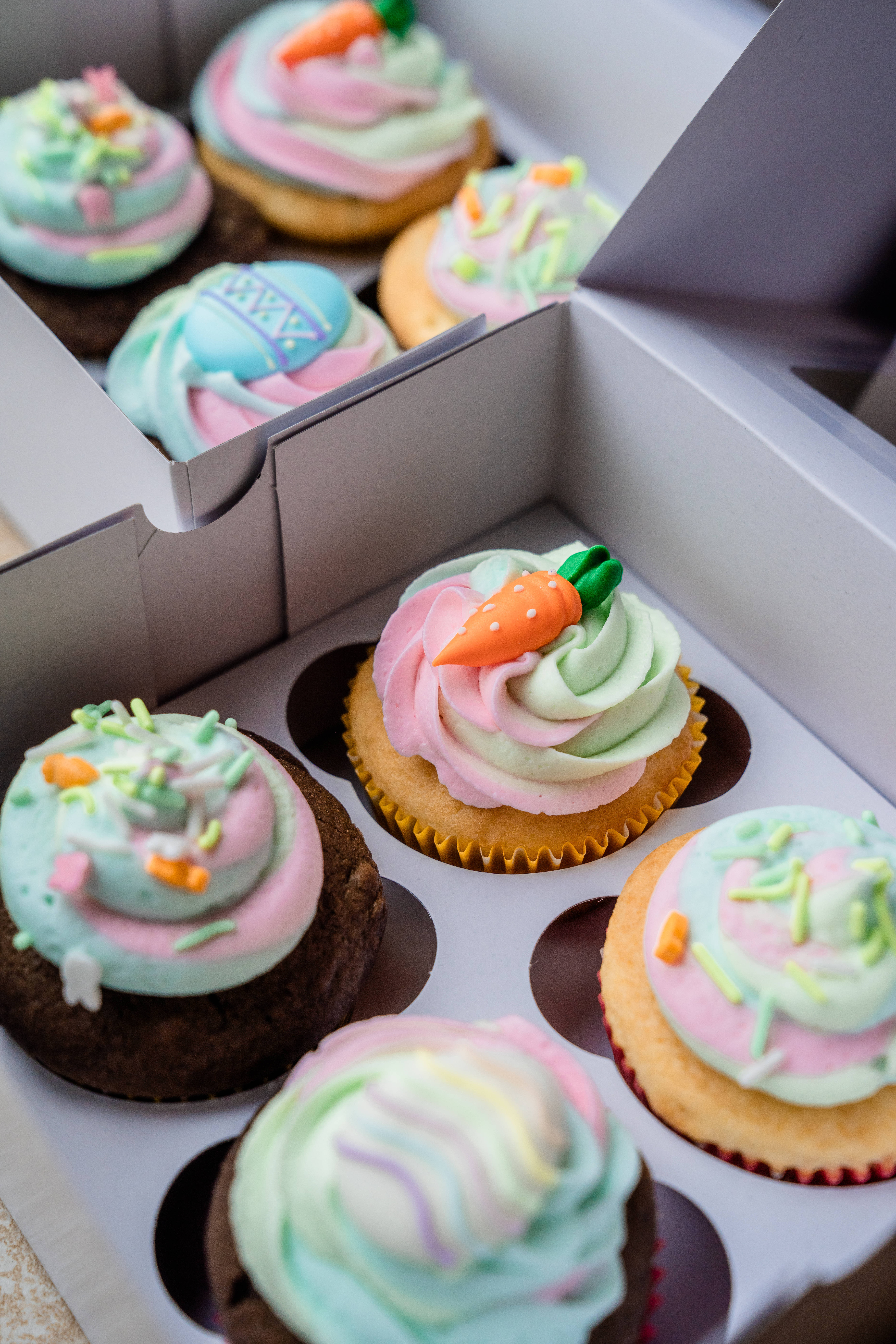 Cupcake 桌布 壁紙 — 紙箱內色彩繽紛的杯子蛋糕，帶有粉彩色糖霜和胡蘿蔔裝飾的特寫。