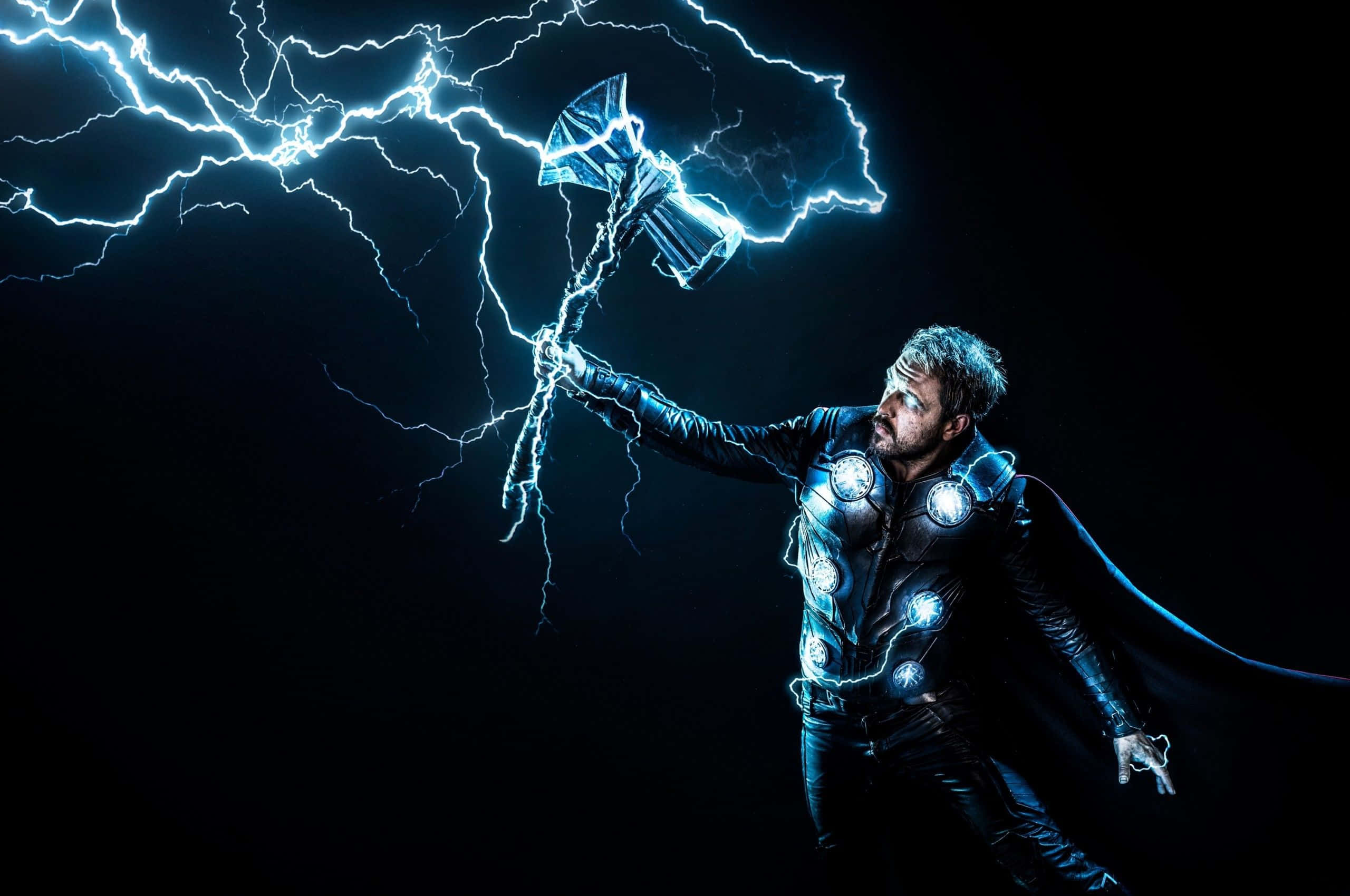 God Of Thunder 桌布 壁紙 — 索爾揮舞著發光的錘子，電光在他周圍的黑暗虛空中劈啪作響。
