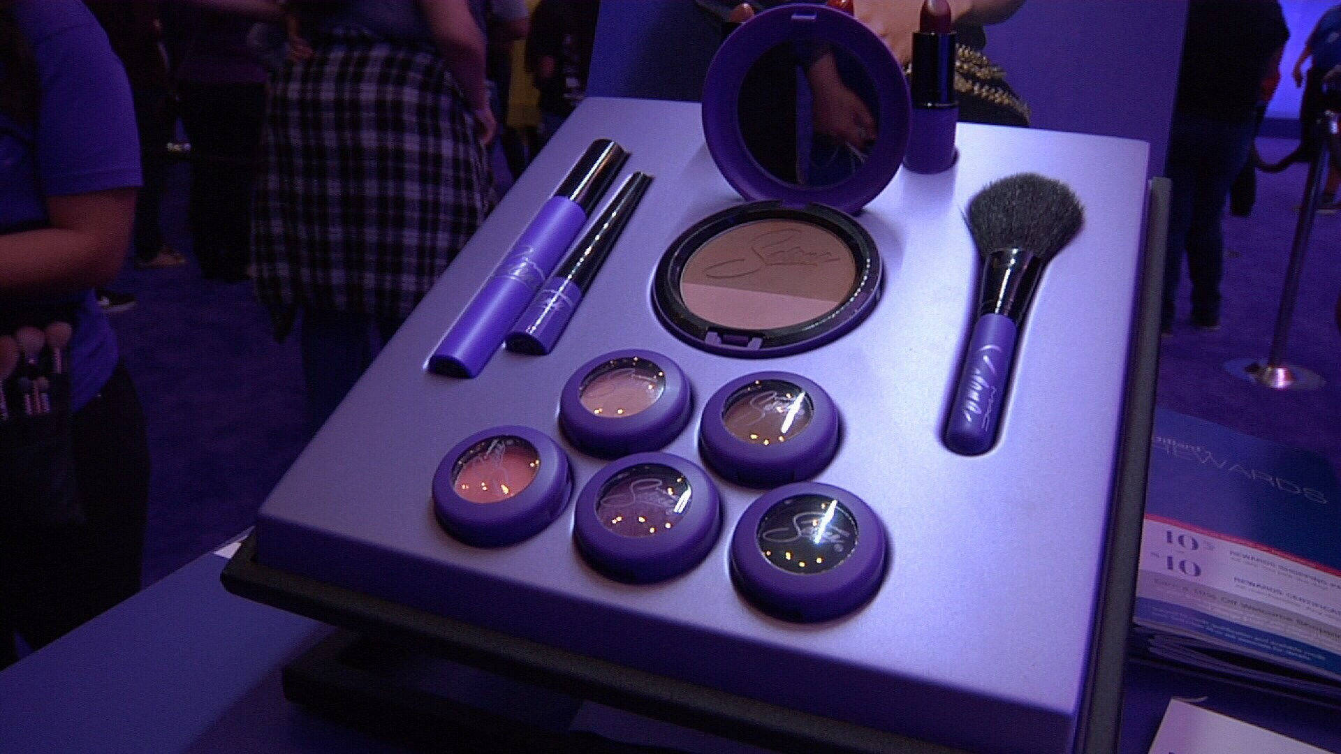 Cosmetics 桌布 壁紙 — 紫色主題化妝品展示，包括粉盒、刷子和鉛筆，排列在會議的亮燈桌上。