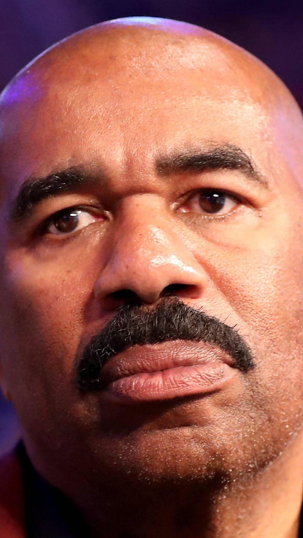 steve harvey 桌布 壁紙 — 紫色燈光下，一位光頭濃鬚男子表情嚴肅向上望的特寫肖像。