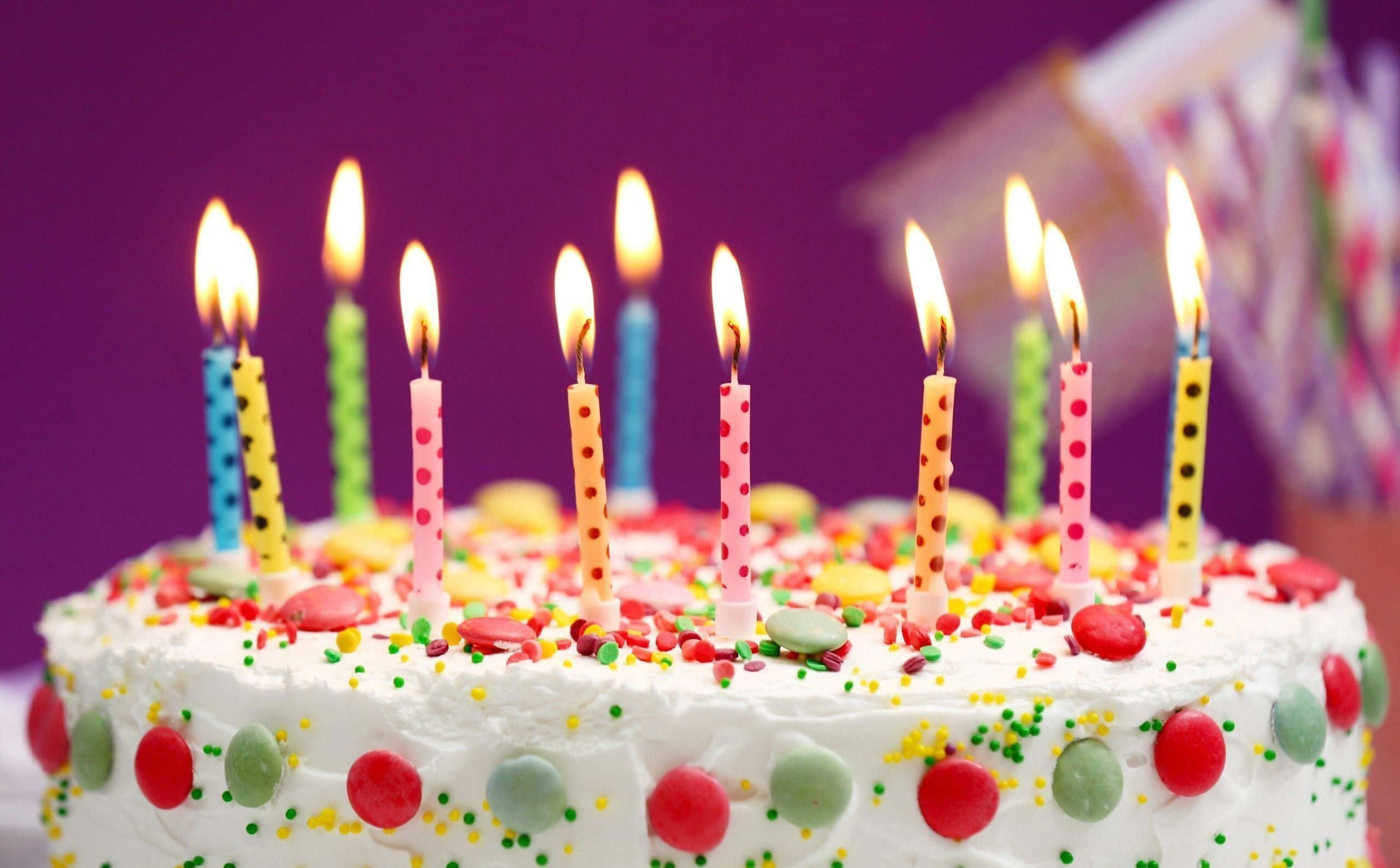 Birthday 桌布 壁紙 — 紫色背景上，一個生日蛋糕的特寫，上面有彩色蠟燭和糖霜裝飾。
