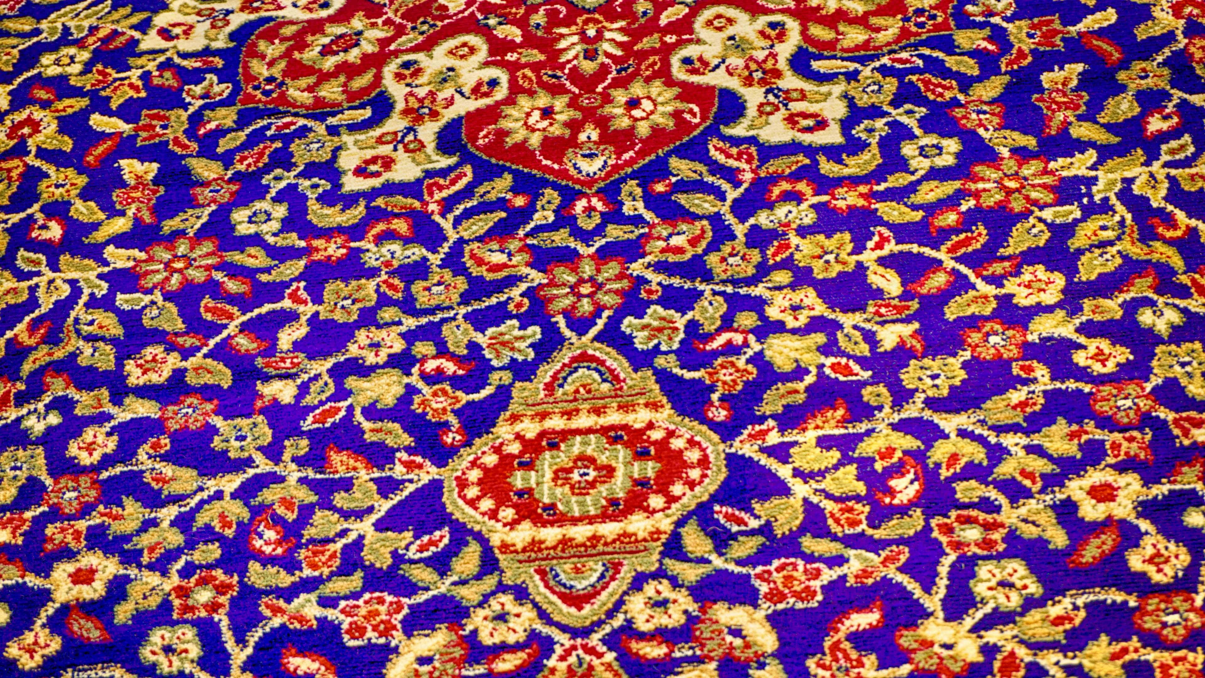 Carpet 桌布 壁紙 — 細節豐富的波斯地毯特寫，深藍色底，紅色花卉圖案和金色點綴。