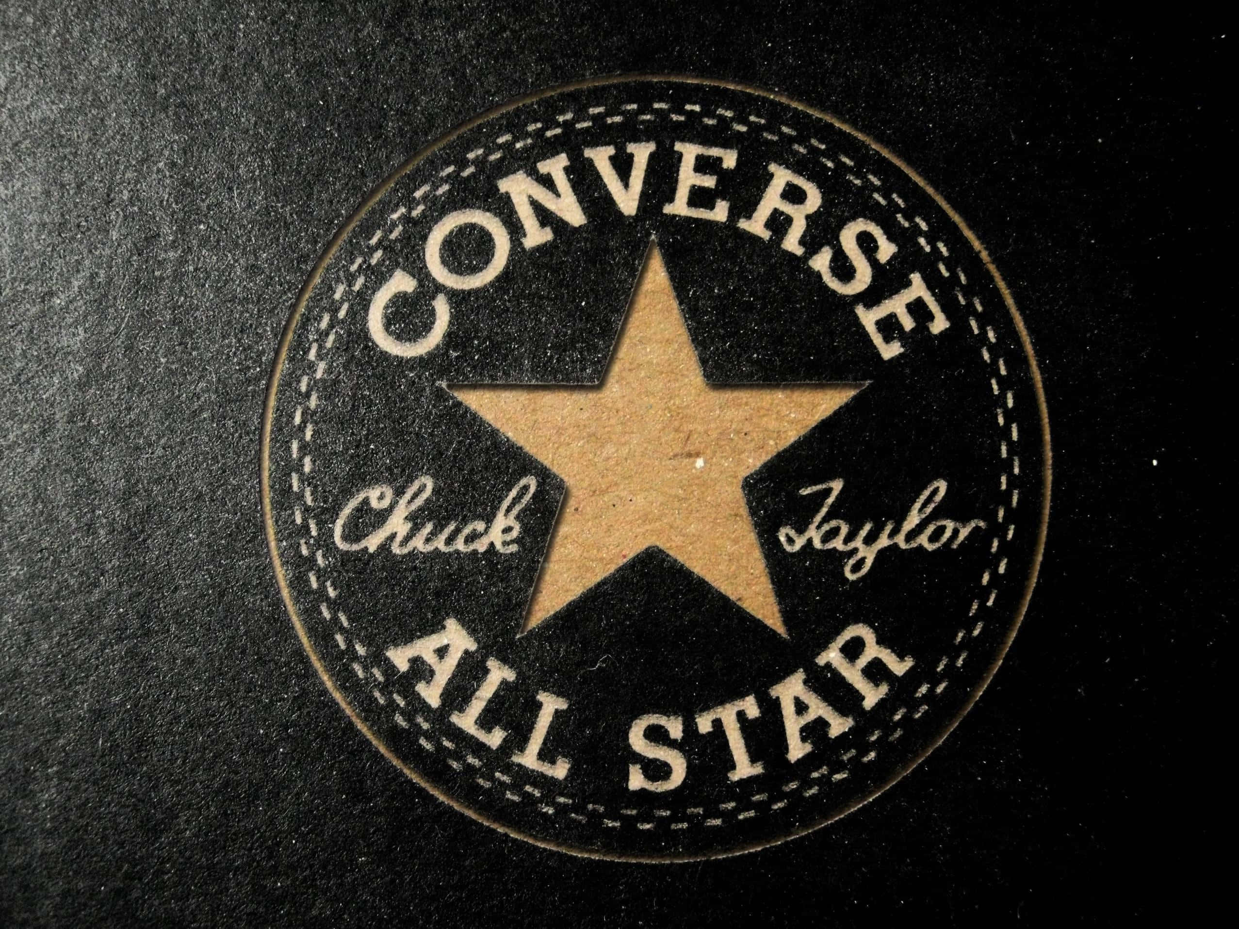 Converse 桌布 壁紙 — 經典 Converse All Star 標誌布章的近距離特寫，在深色紋理布料上帶有米色星星和縫線。