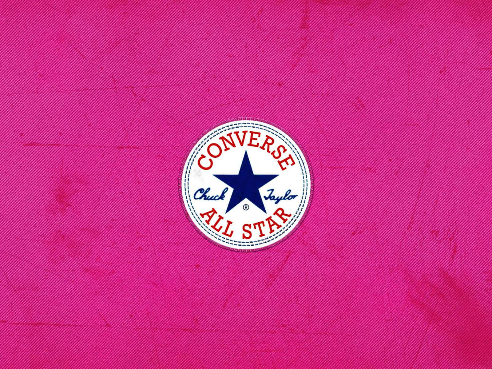 Converse Logo 桌布 壁紙 — 經典 Converse All Star 標誌置於充滿活力的粉紅色紋理布料背景中央，帶有可見的刮痕。