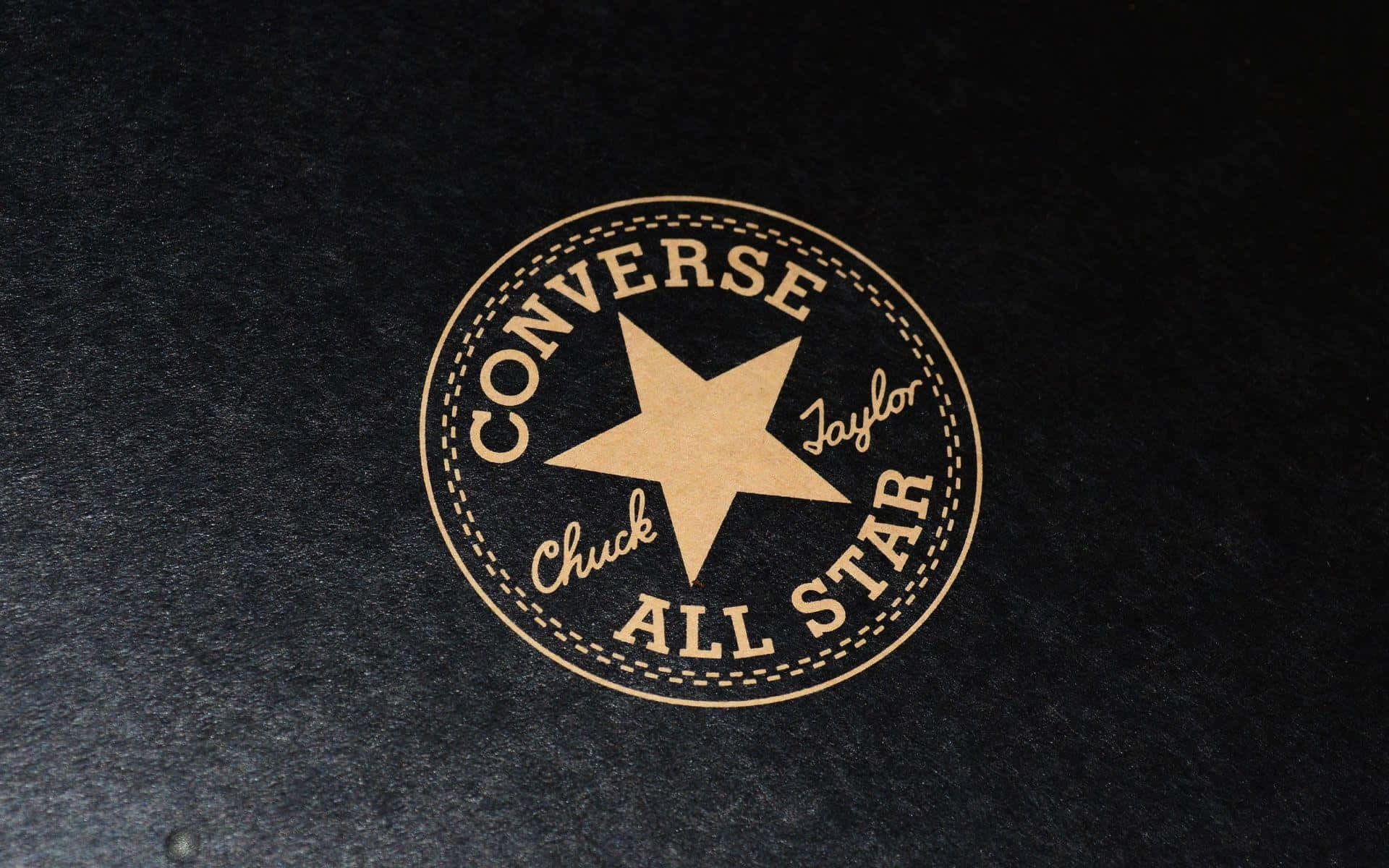 Converse 桌布 壁紙 — 經典 Converse Chuck Taylor All Star 標誌，以棕褐色呈現於有紋理的黑色布料上。