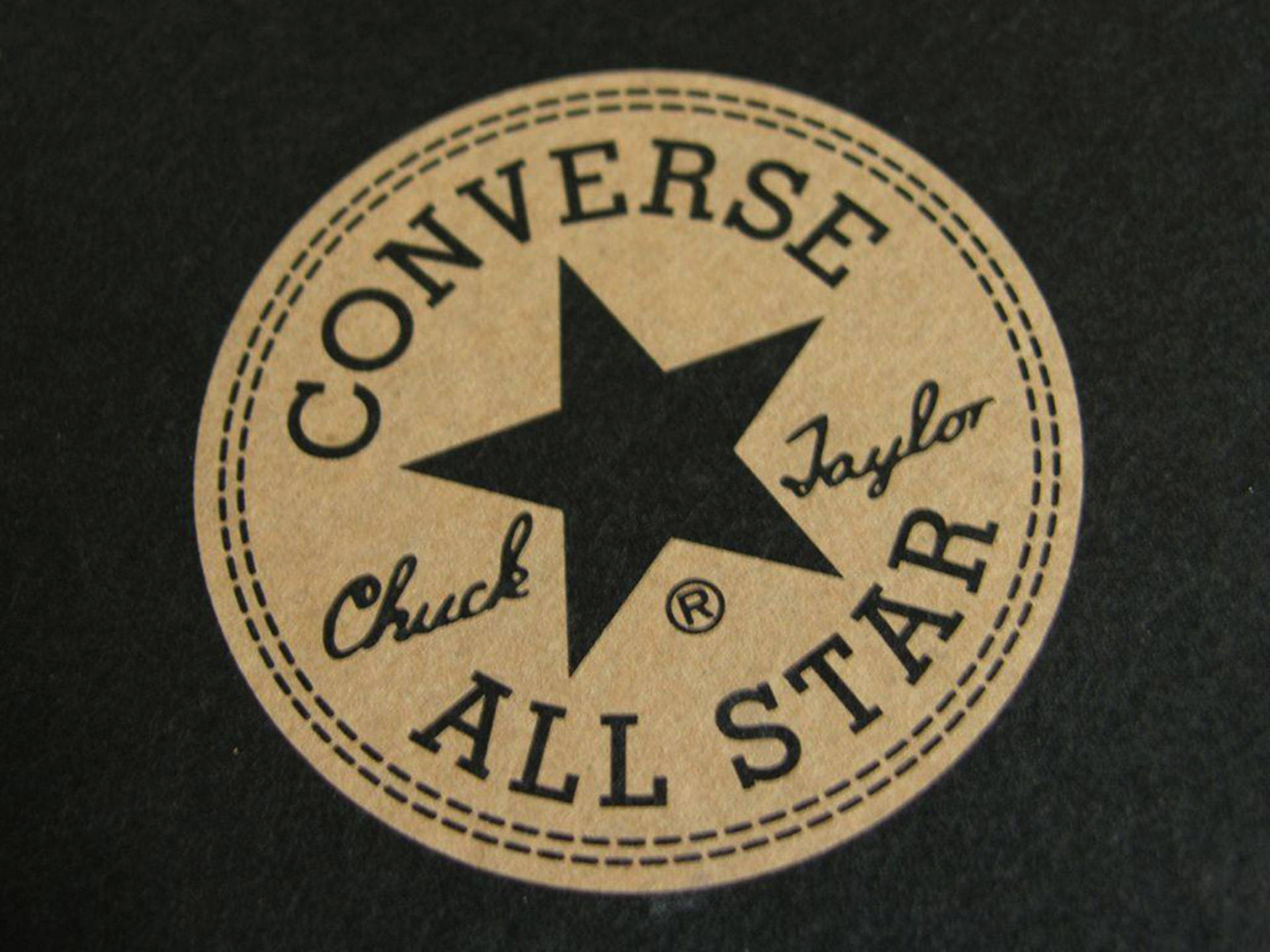 Converse 標誌 桌布 壁紙 — 經典 Converse Chuck Taylor All Star 標誌貼片在深色布料上的特寫，帶有縫合邊框。