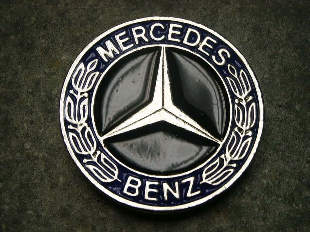 Mercedes Benz Logo 桌布 壁紙 — 經典 Mercedes-Benz 標誌的特寫，黑色背景上有一個銀色三叉星，周圍環繞著月桂花環和藍色琺瑯。