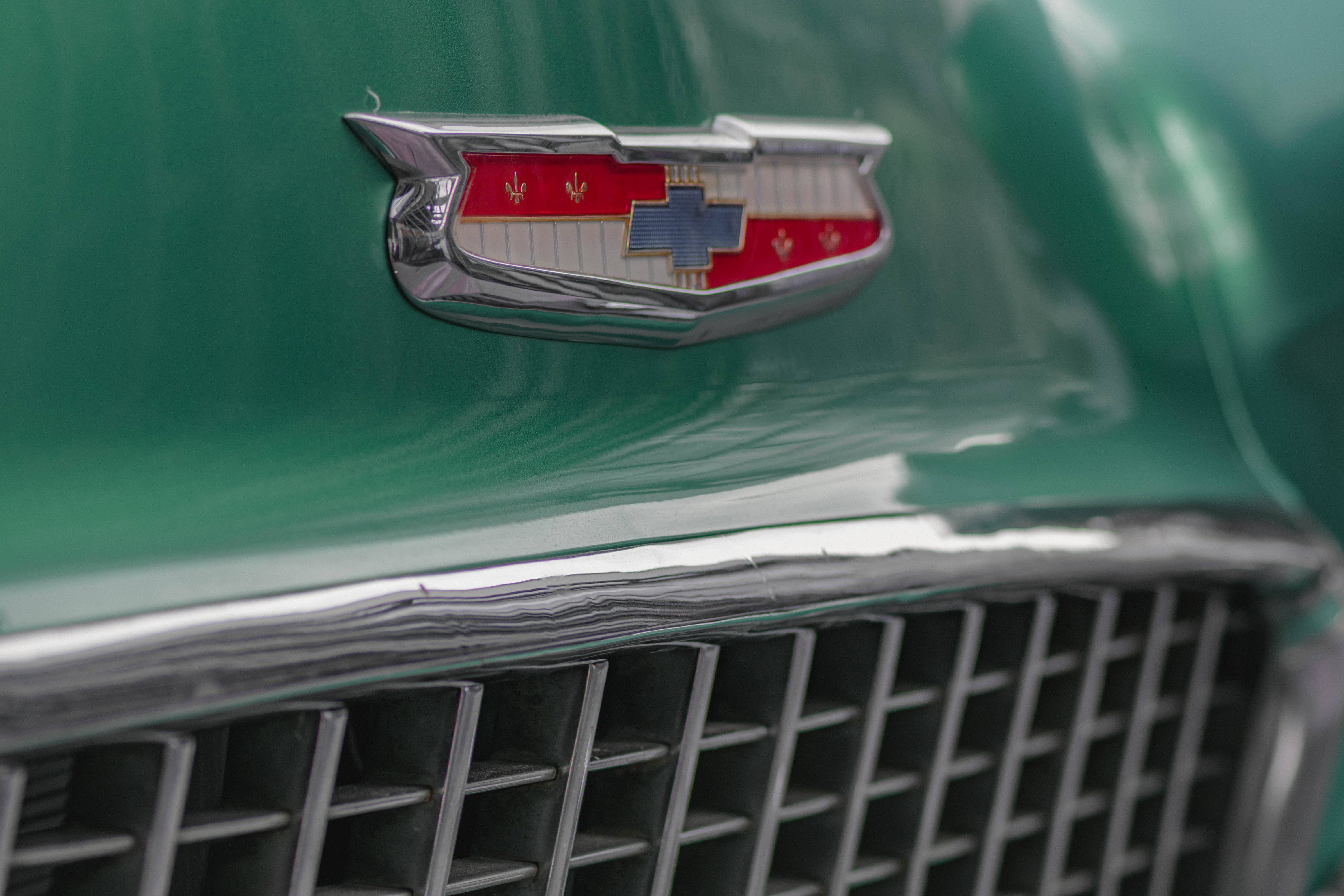 Chevrolet Logo 桌布 壁紙 — 經典凱迪拉克標誌在光澤綠色引擎蓋上閃耀，位於鍍鉻格柵上方的特寫。