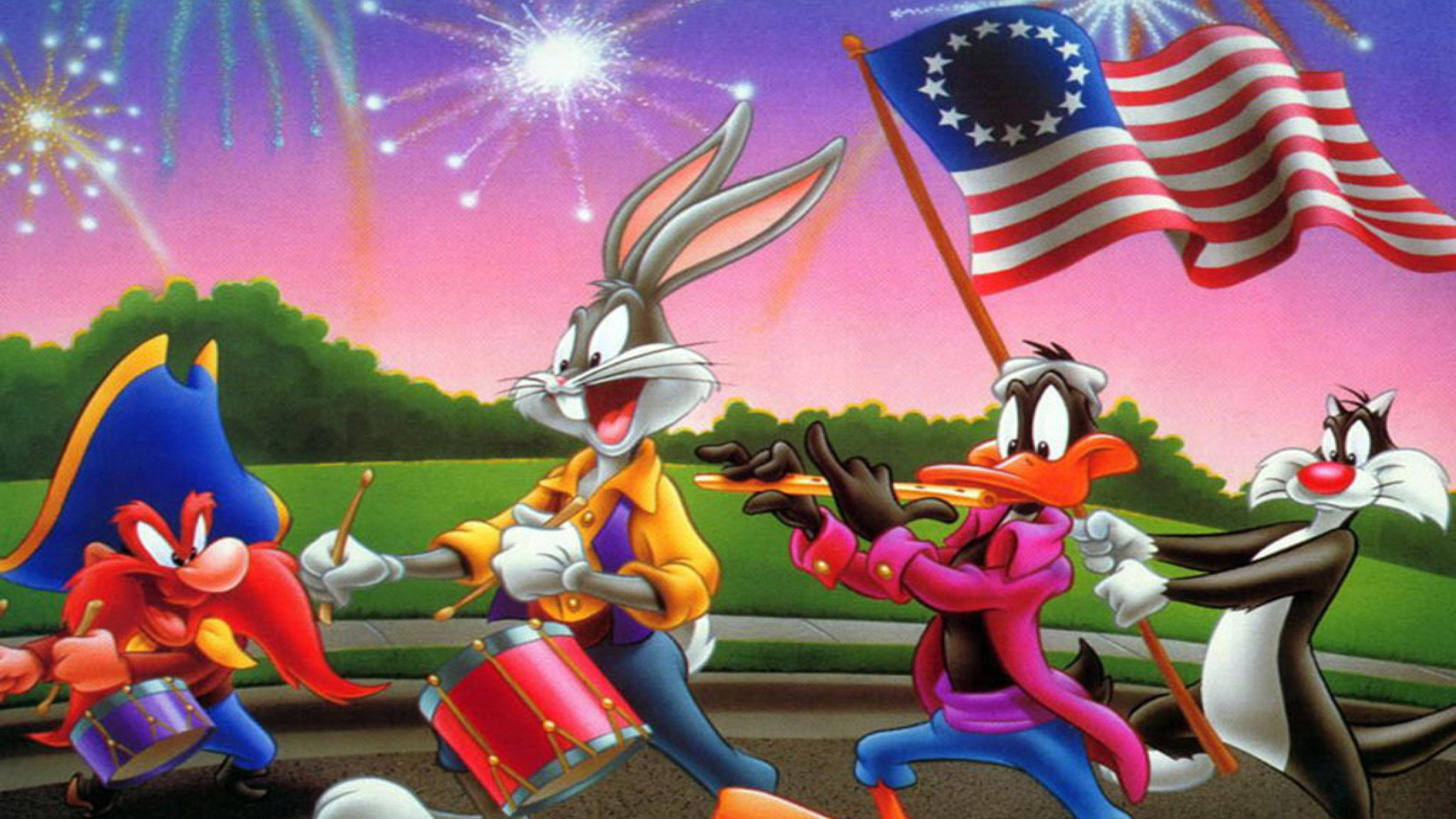 Yosemite Sam 桌布 壁紙 — 經典卡通角色在暮色天空下，伴隨色彩繽紛的煙火，歡樂地敲著鼓、揮舞旗幟遊行。