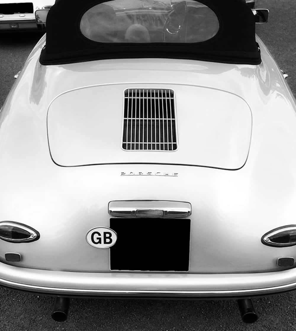 Car Hood 桌布 壁紙 — 經典白色保時捷356敞篷車的後視圖，搭配黑色軟頂和GB貼紙，黑白風格。