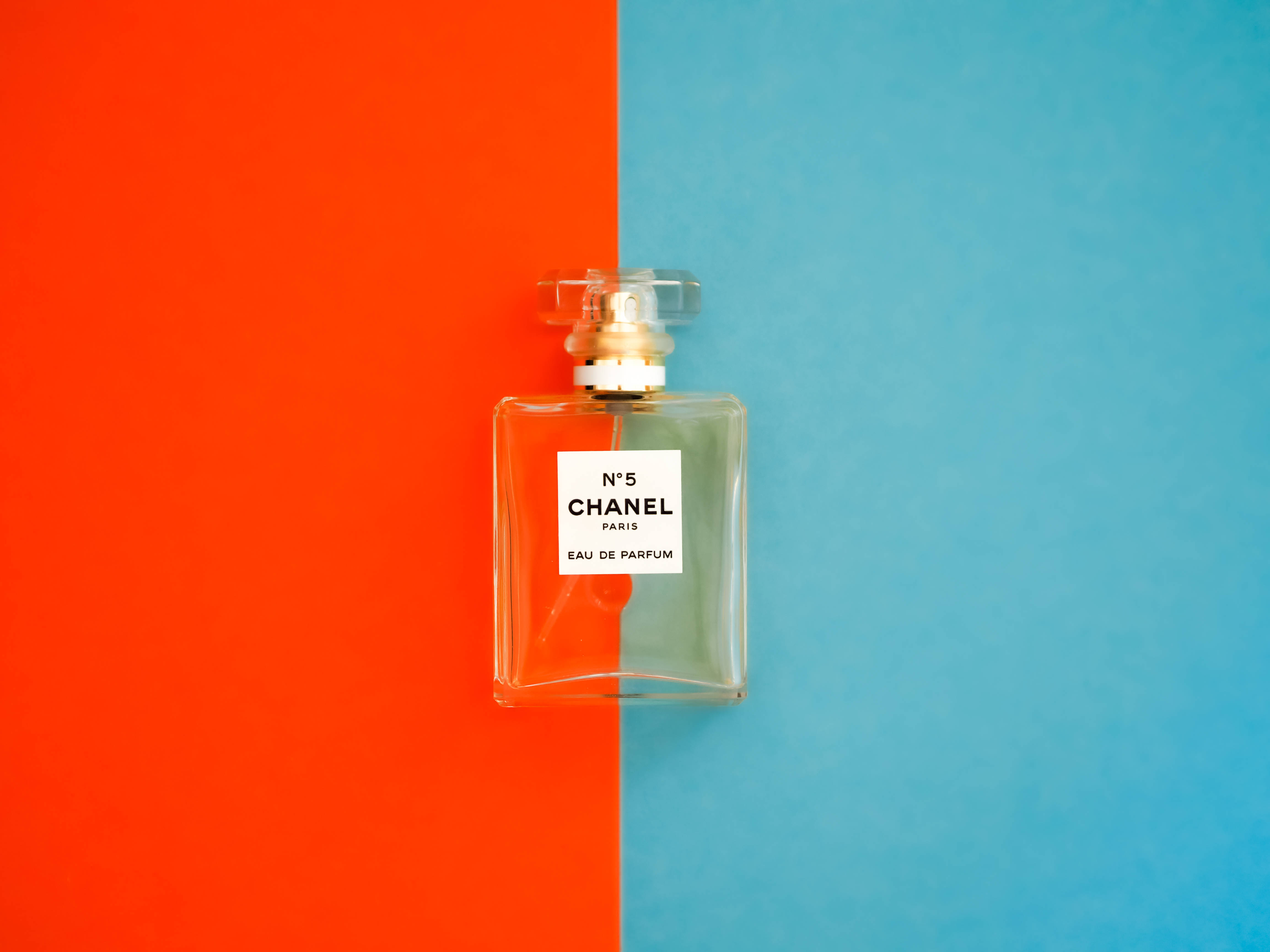 Chanel 桌布 壁紙 — 經典的 Chanel No 5 香水瓶居中放置在橙色和藍色的鮮明分割背景上。