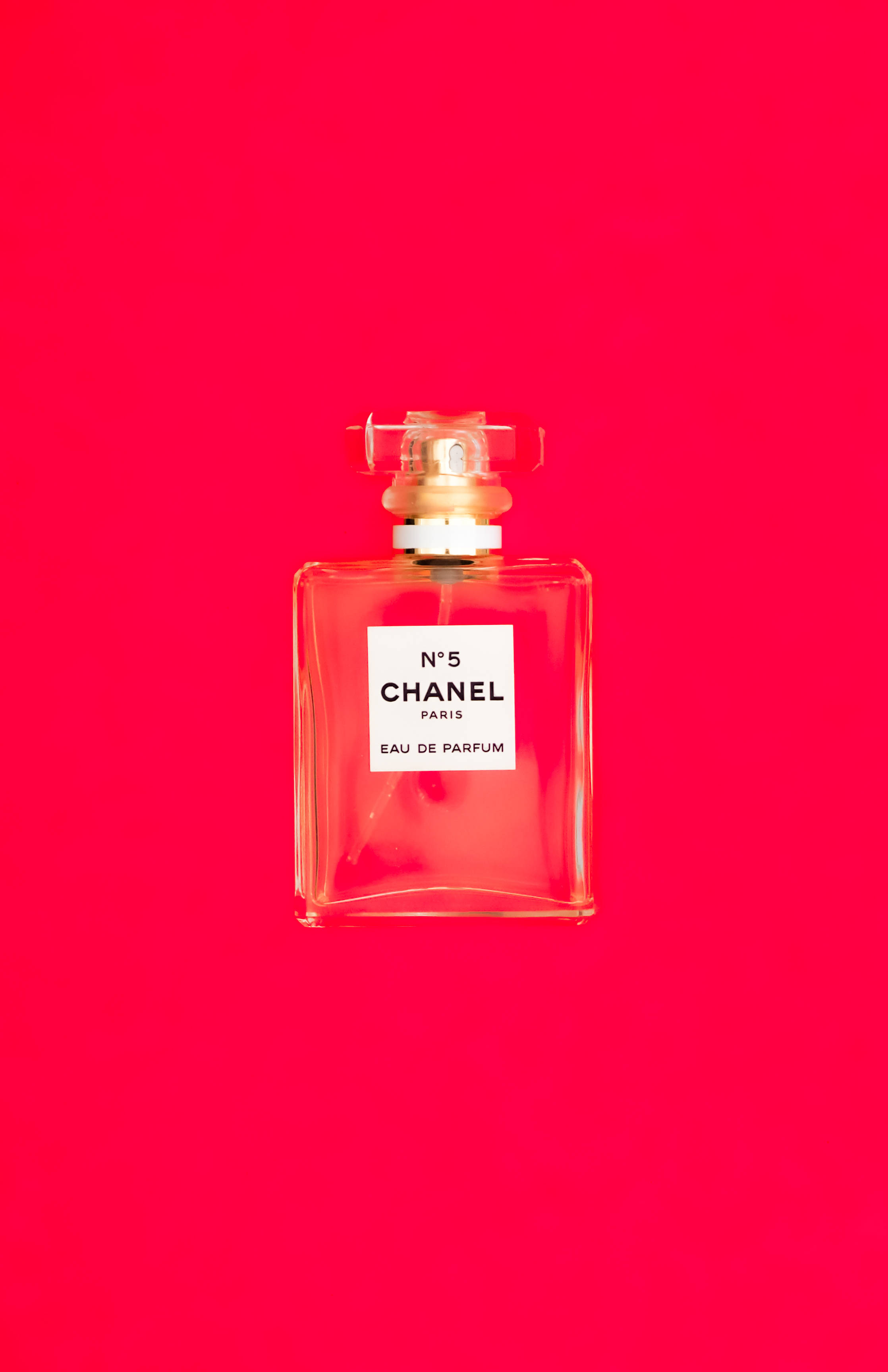 Chanel 桌布 壁紙 — 經典的Chanel No 5香水瓶置於大膽飽和的紅色背景中央。