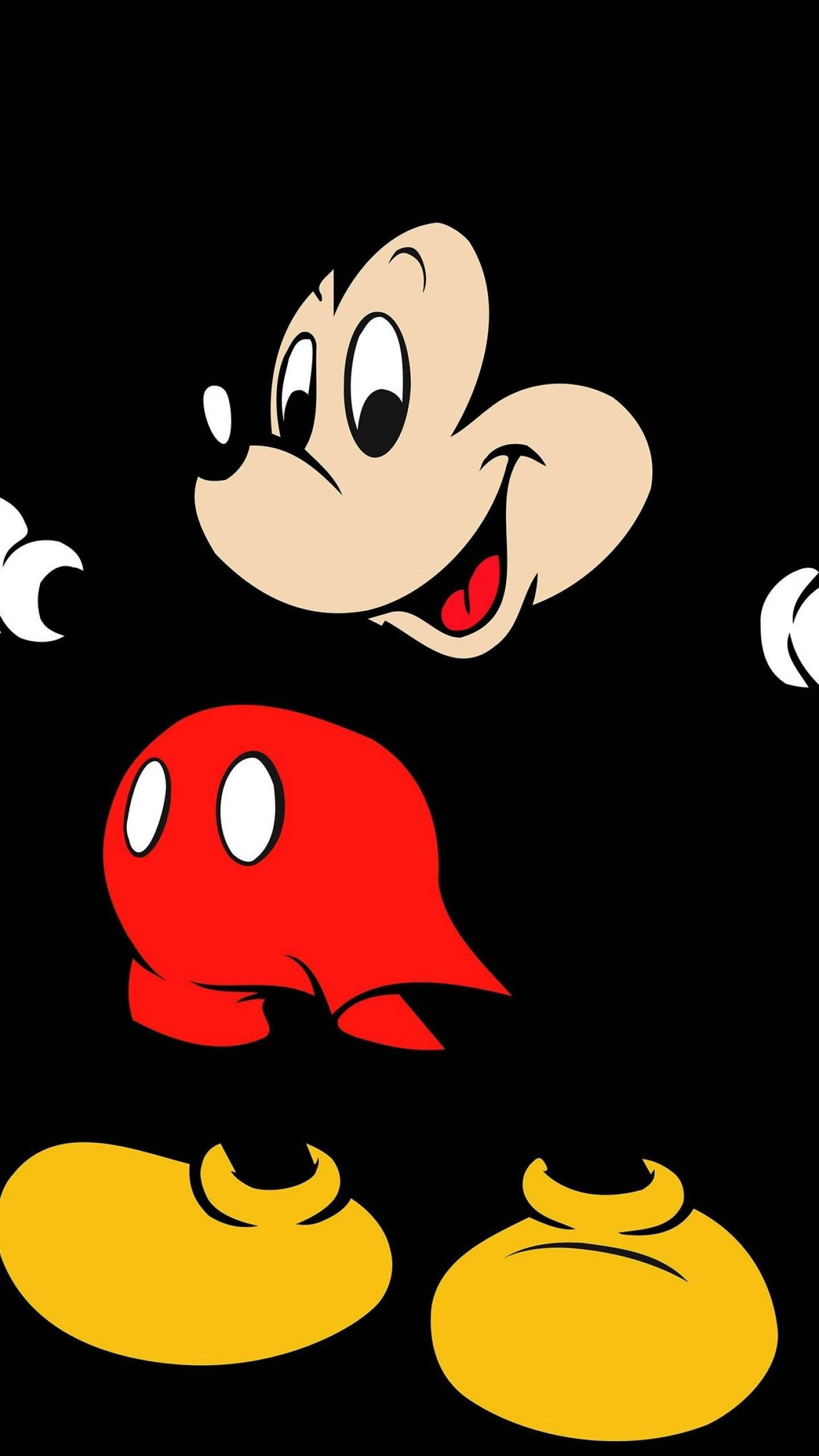 Mickey 桌布 壁紙 — 經典米奇老鼠卡通角色，穿著紅色短褲和黃色鞋子，背景為黑色。