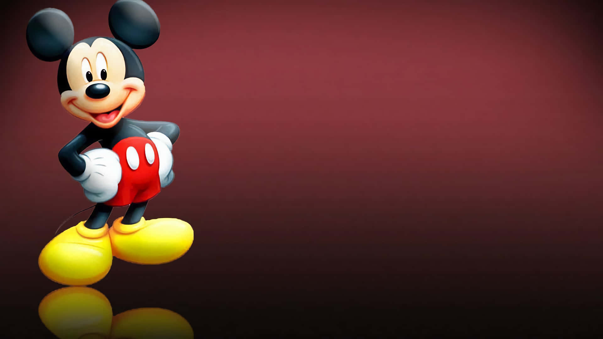 Mickey Mouse Desktop 桌布 壁紙 — 經典米奇老鼠穿著標誌性的紅色短褲和黃色鞋子，在深栗色漸變背景上愉快地微笑。
