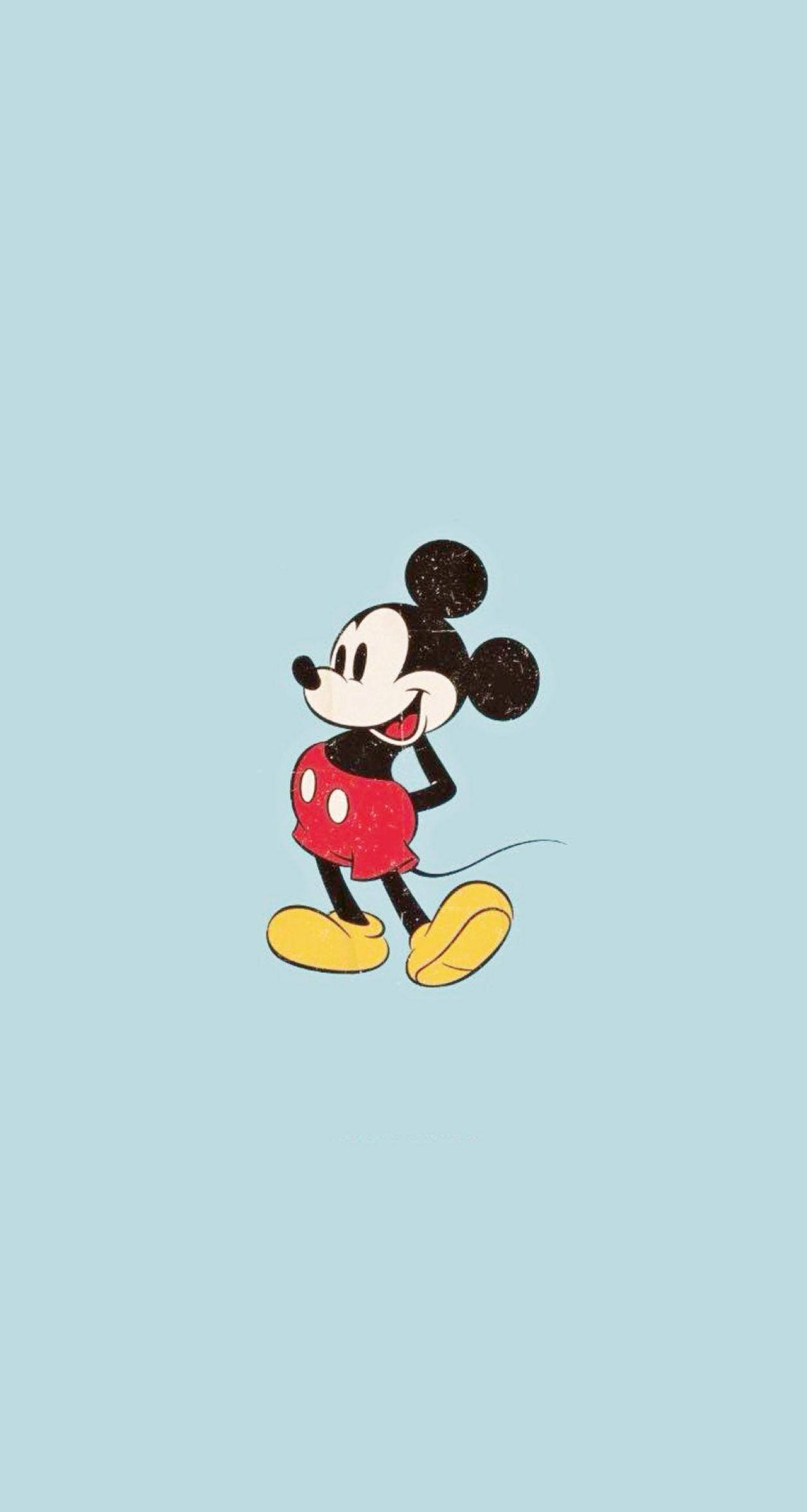 Mickey 桌布 壁紙 — 經典米奇老鼠穿著紅色短褲和黃色鞋子，在柔和的藍色背景前開心地微笑。