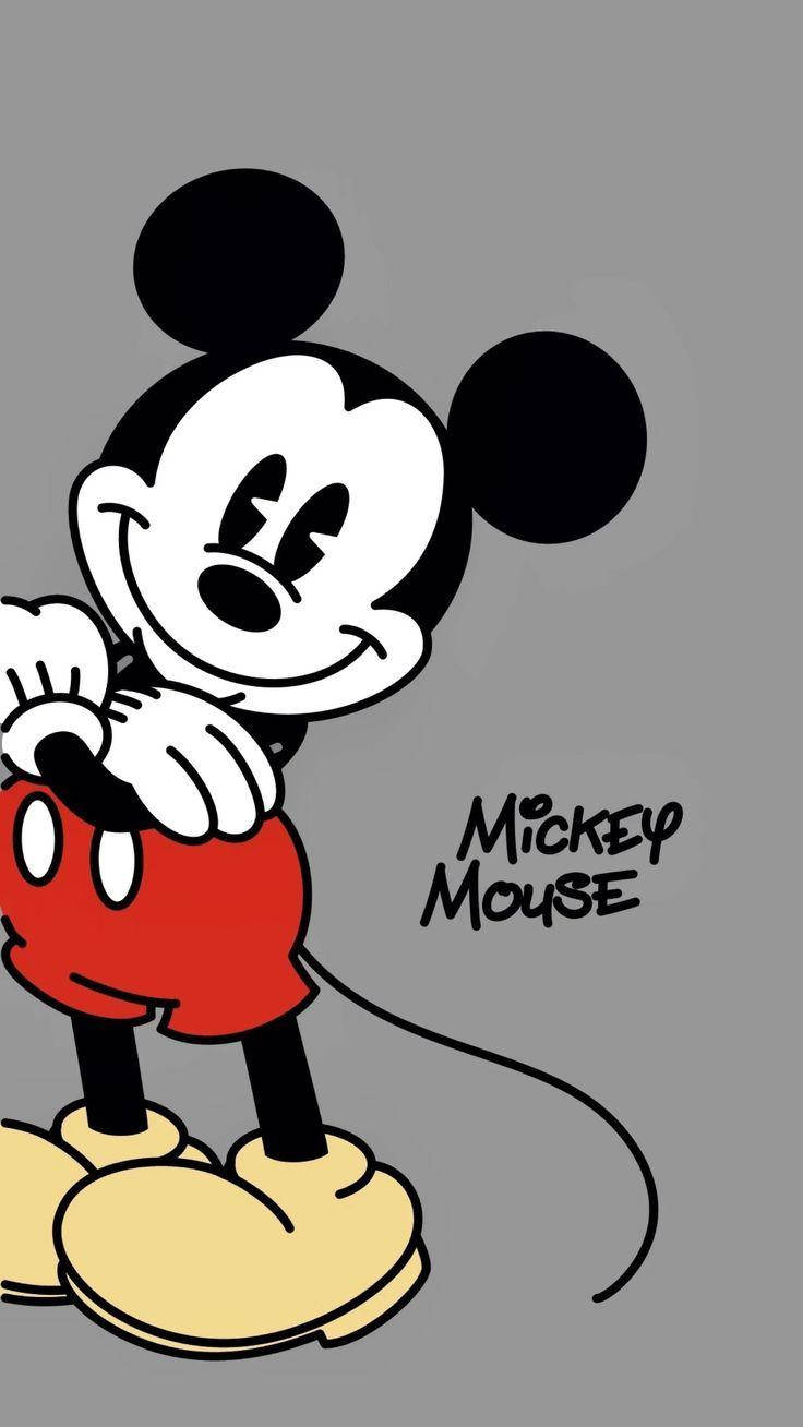 Mickey 桌布 壁紙 — 經典米奇老鼠穿著紅色短褲和黃色鞋子，在純灰色背景前開心地微笑。