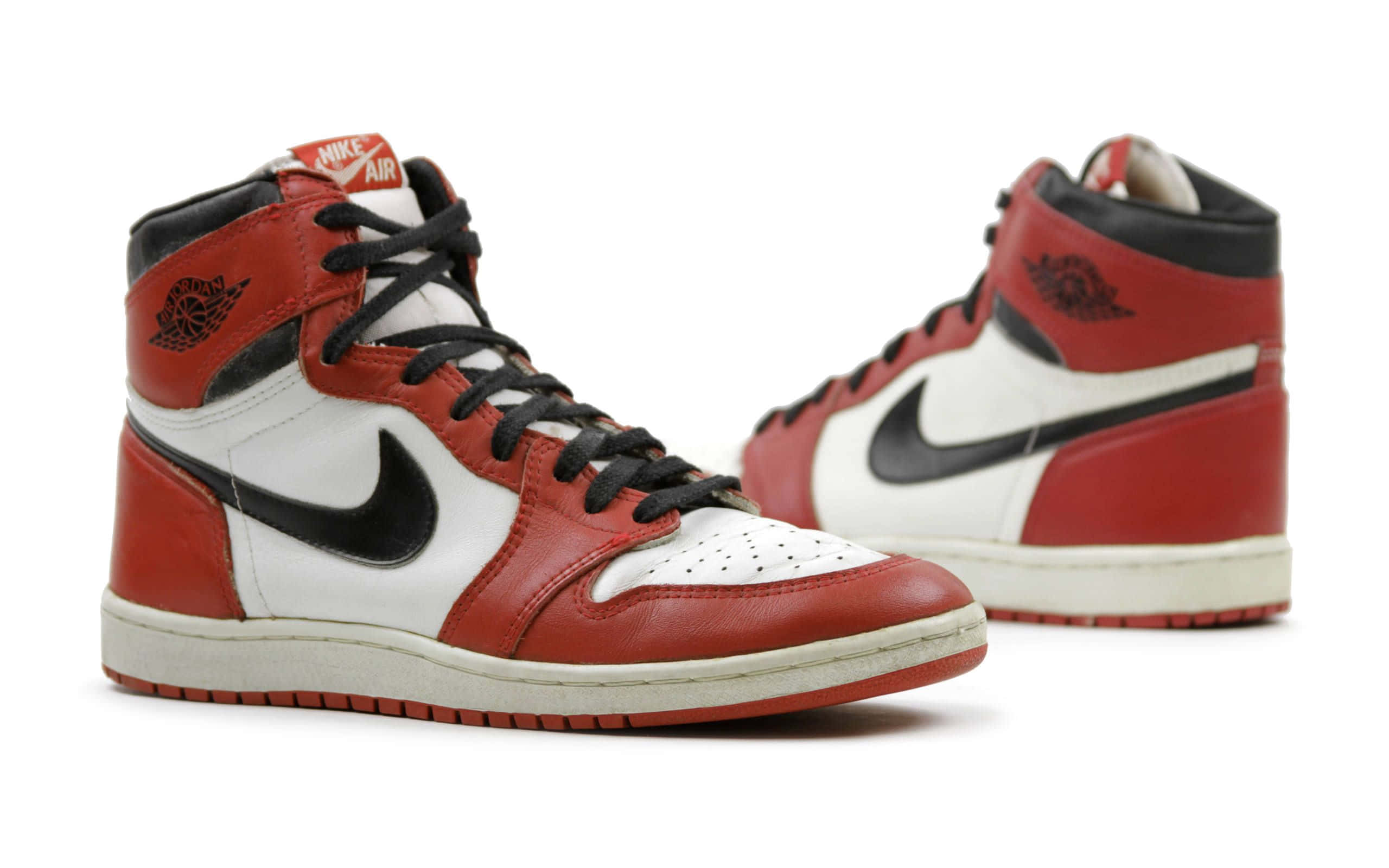 桌布 壁紙 — 經典紅、白、黑色高筒運動鞋，帶有標誌性 Nike 勾勾和 Jordan 標誌，展示在潔白背景上。