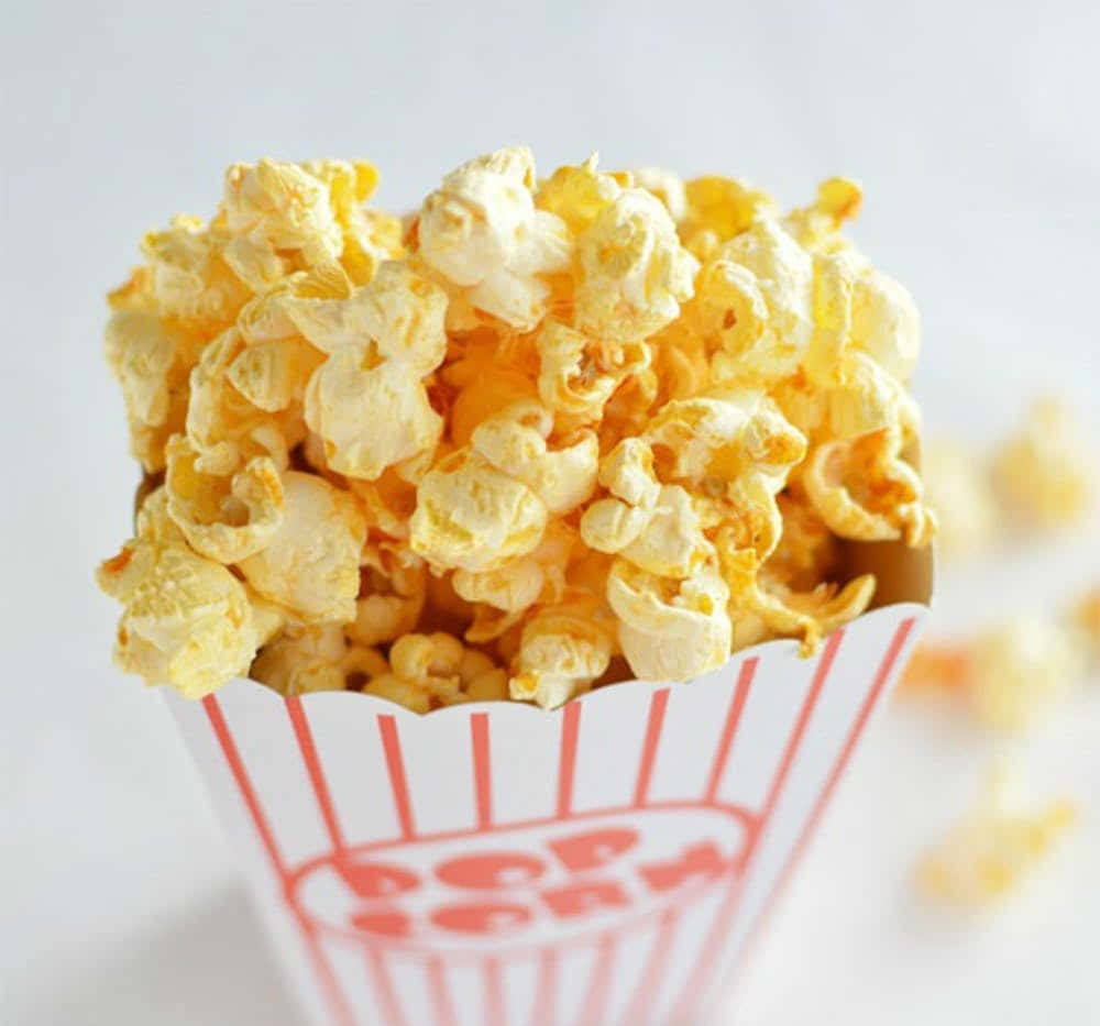 Popcorn 桌布 壁紙 — 經典紅白條紋紙桶中溢出金黃奶油爆米花的特寫。