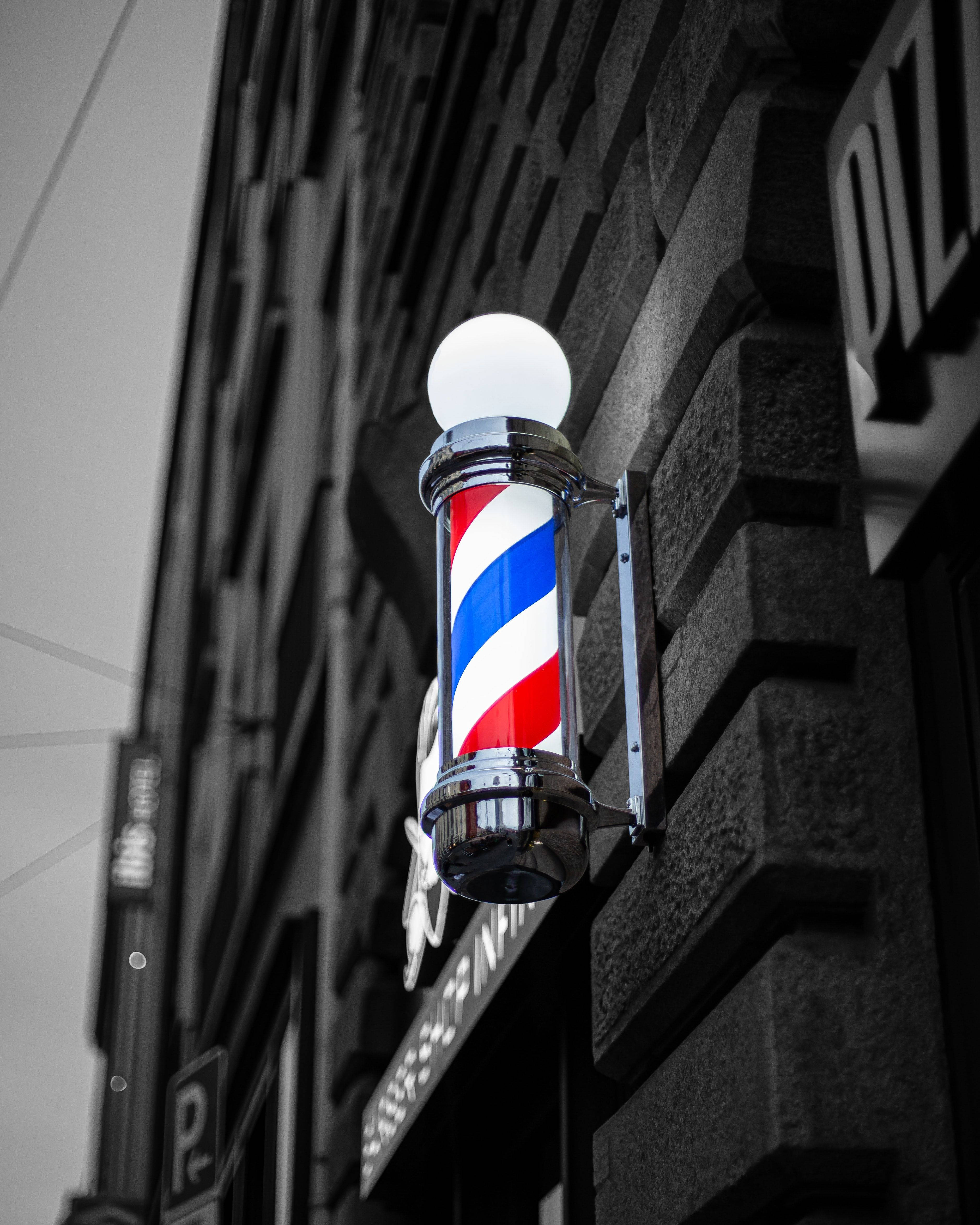 Barber 桌布 壁紙 — 經典紅白藍理髮柱在單色磚建築外牆上閃耀。