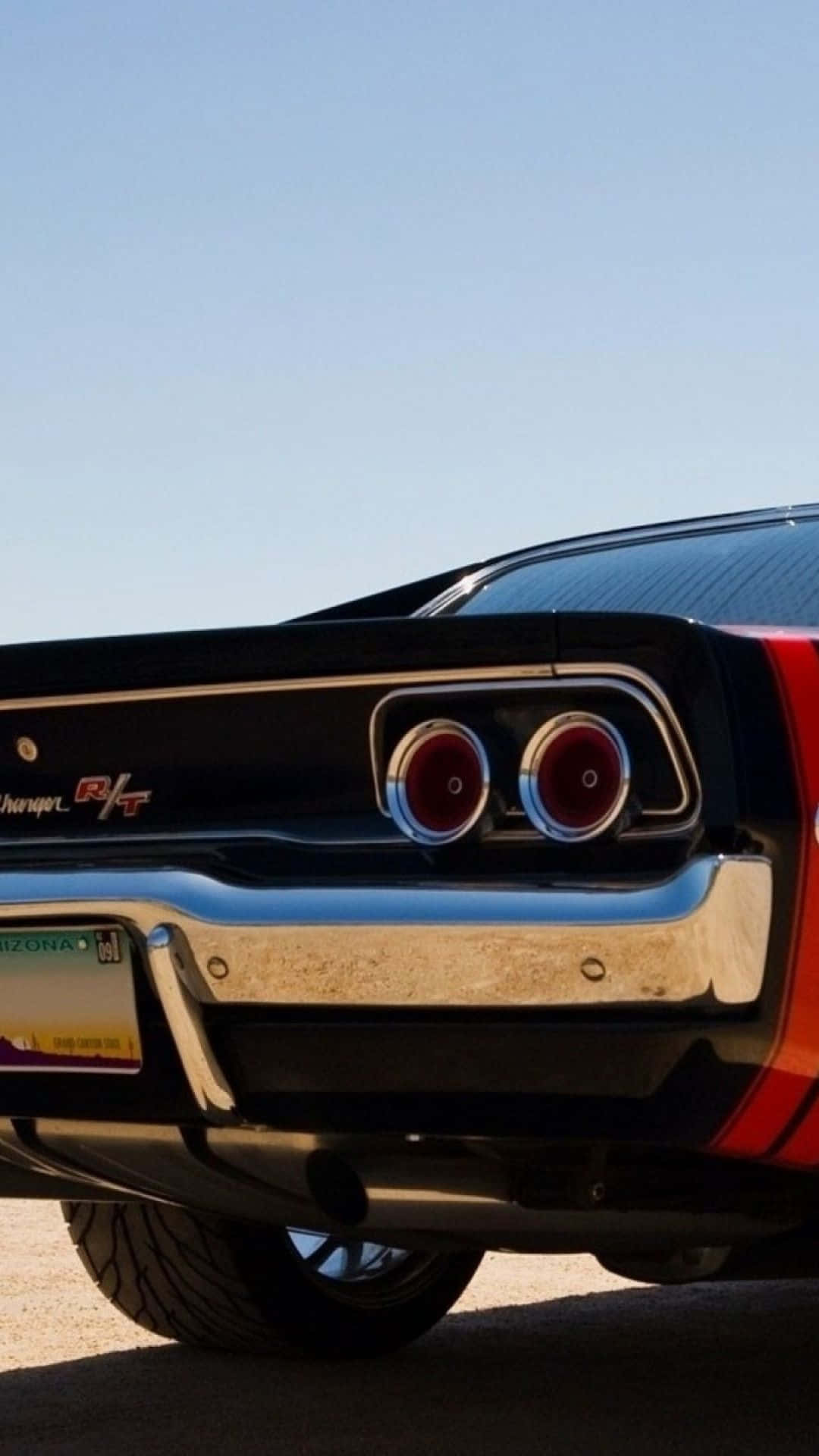 Vintage Car 桌布 壁紙 — 經典黑色和紅色道奇 Charger RT 的後視圖，帶有鍍鉻細節和圓形尾燈，在晴朗的藍天下。