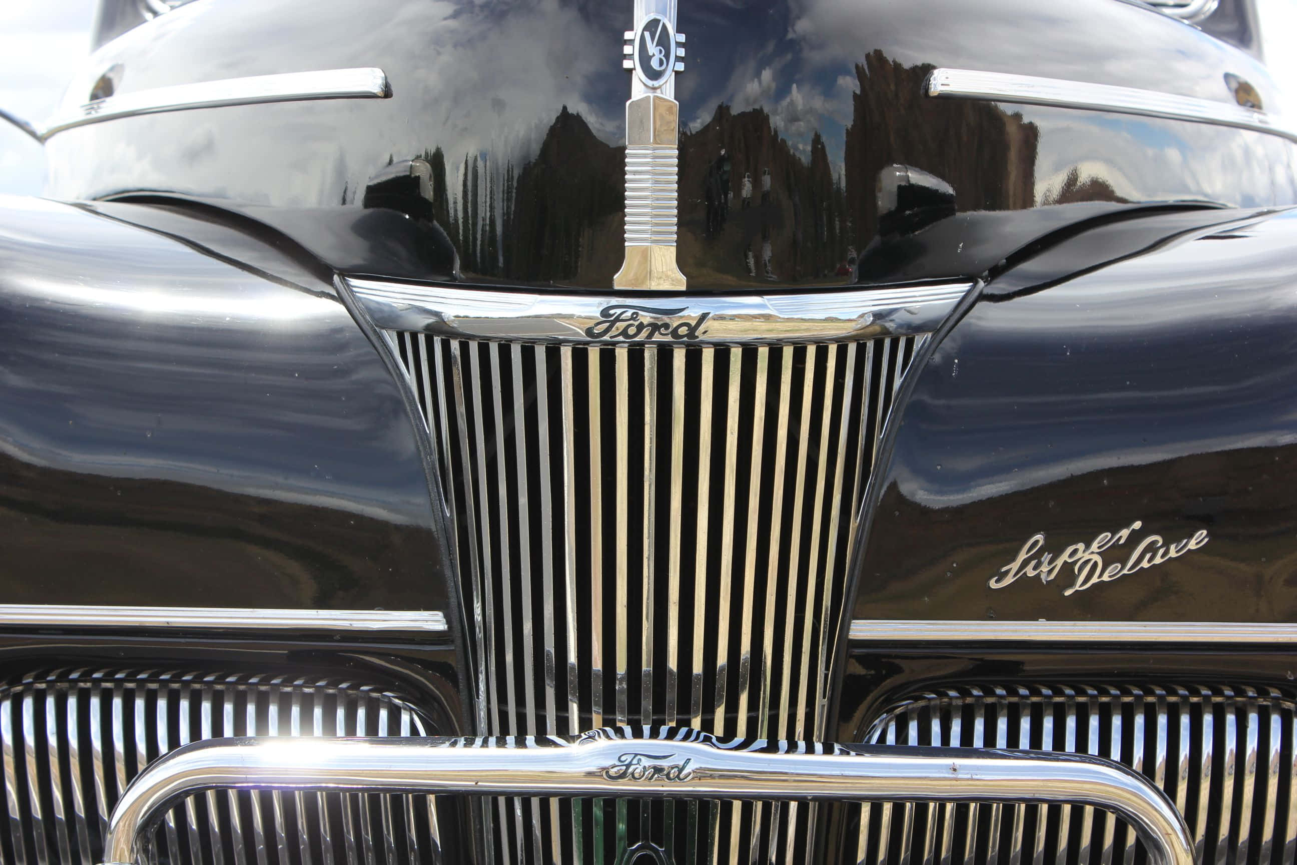 Car Grill 桌布 壁紙 — 經典黑色福特 Super Deluxe 格柵的特寫，在明亮的日光下反射崎嶇的峽谷懸崖。