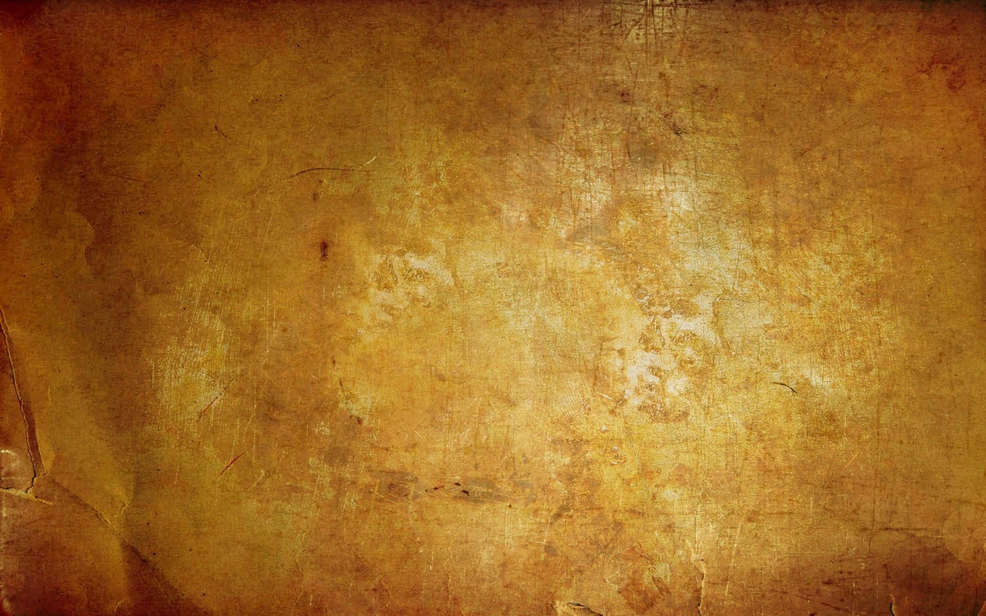 Yellow Grunge 桌布 壁紙 — 經風化的金棕色紋理表面，帶有刮痕和褪色斑塊，類似舊羊皮紙。