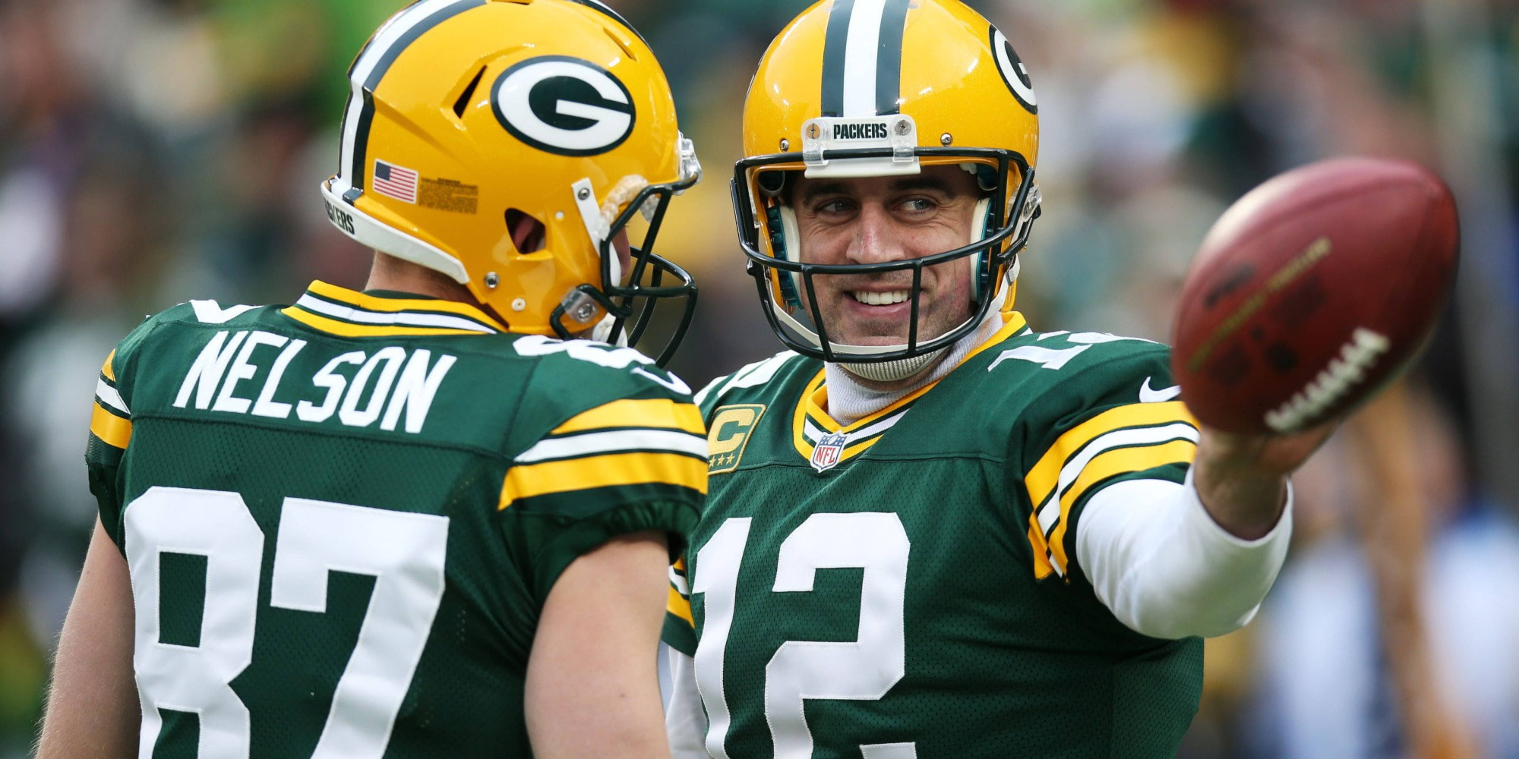 Aaron Rodgers 桌布 壁紙 — 綠灣包裝工四分衛亞倫·羅傑斯在球場上拿著橄欖球，與接球手賈里德·尼爾森並肩微笑。