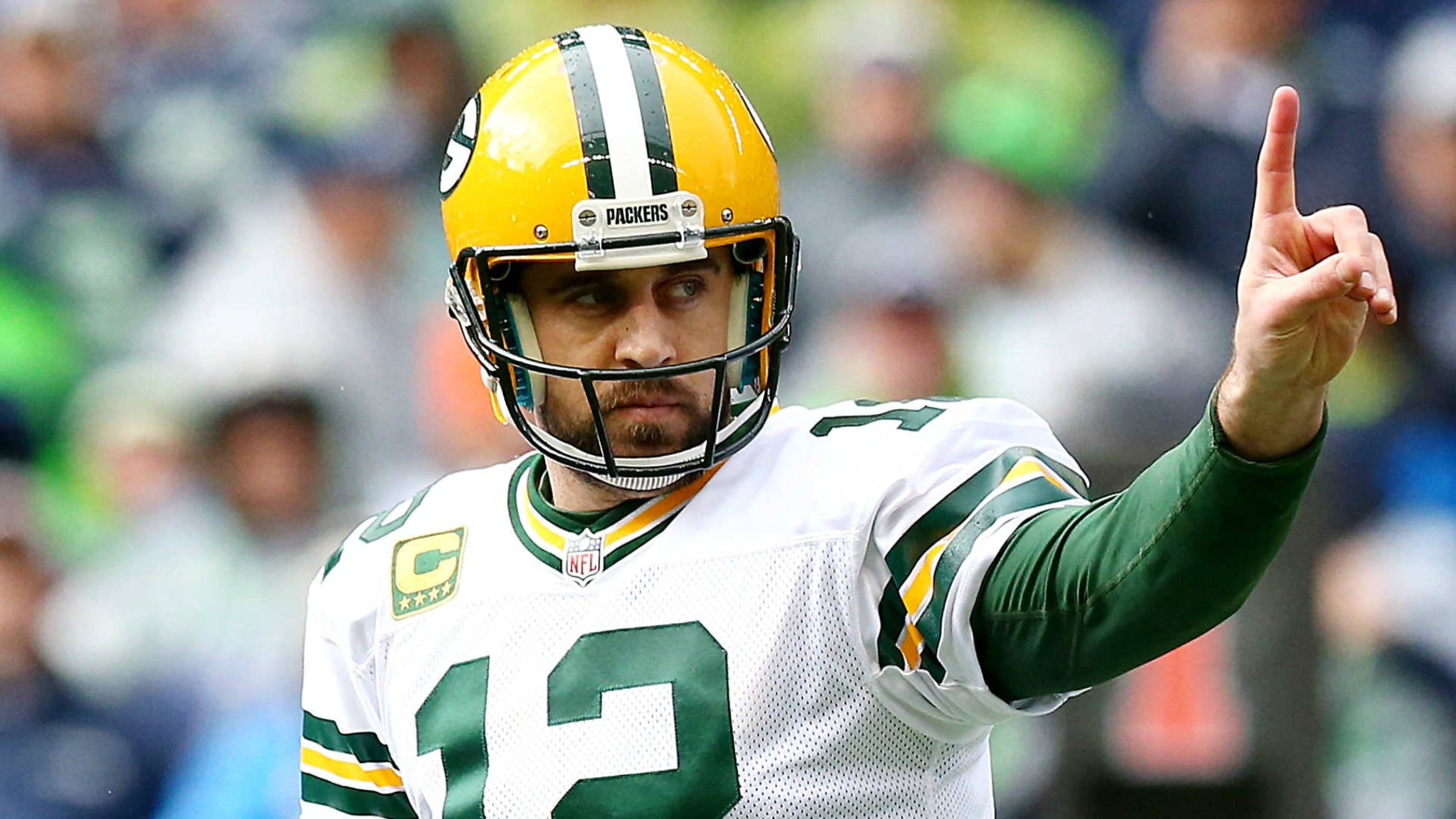 Aaron Rodgers 桌布 壁紙 — 綠灣包裝工四分衛亞倫·羅傑斯身穿白色和綠色球衣在比賽中向上指。