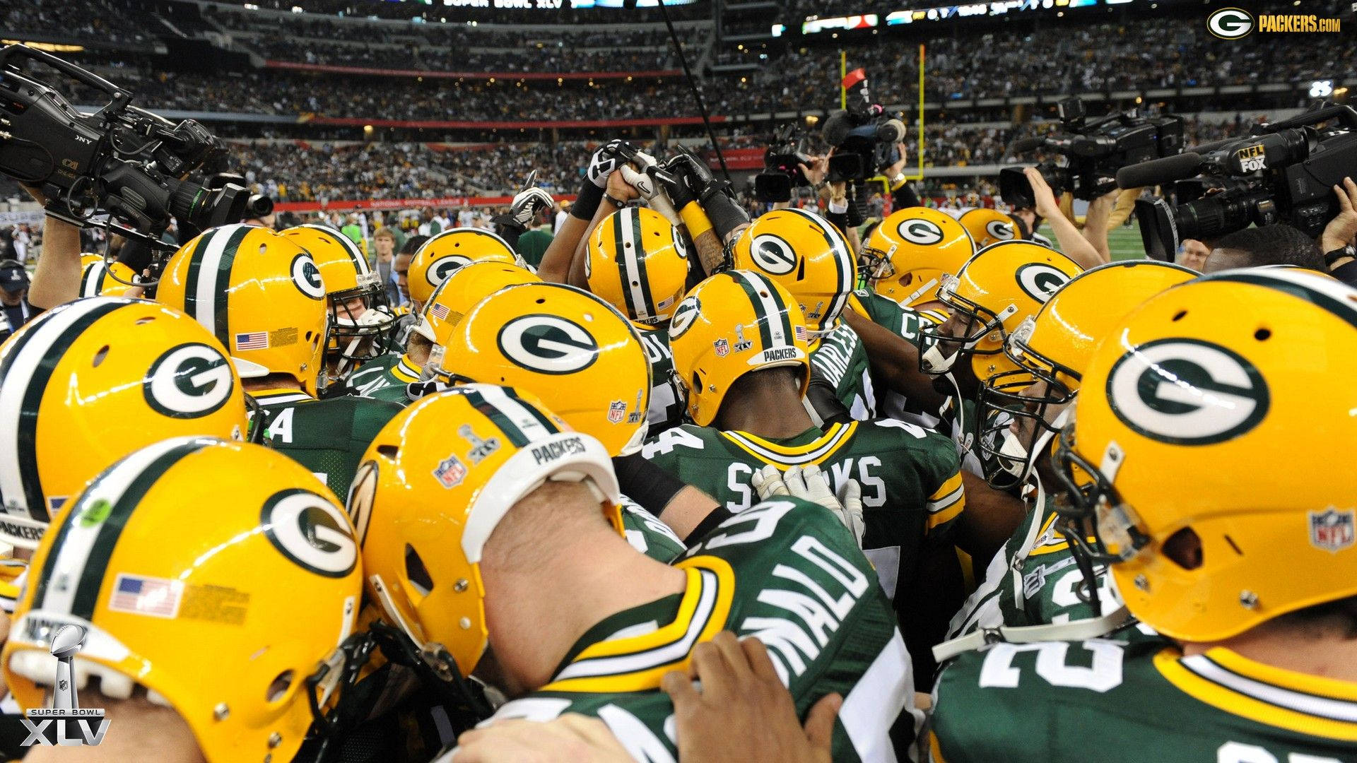 Packers 桌布 壁紙 — 綠灣包裝工美式足球員在比賽中戴著黃色頭盔和綠色球衣緊密地聚集在場上。