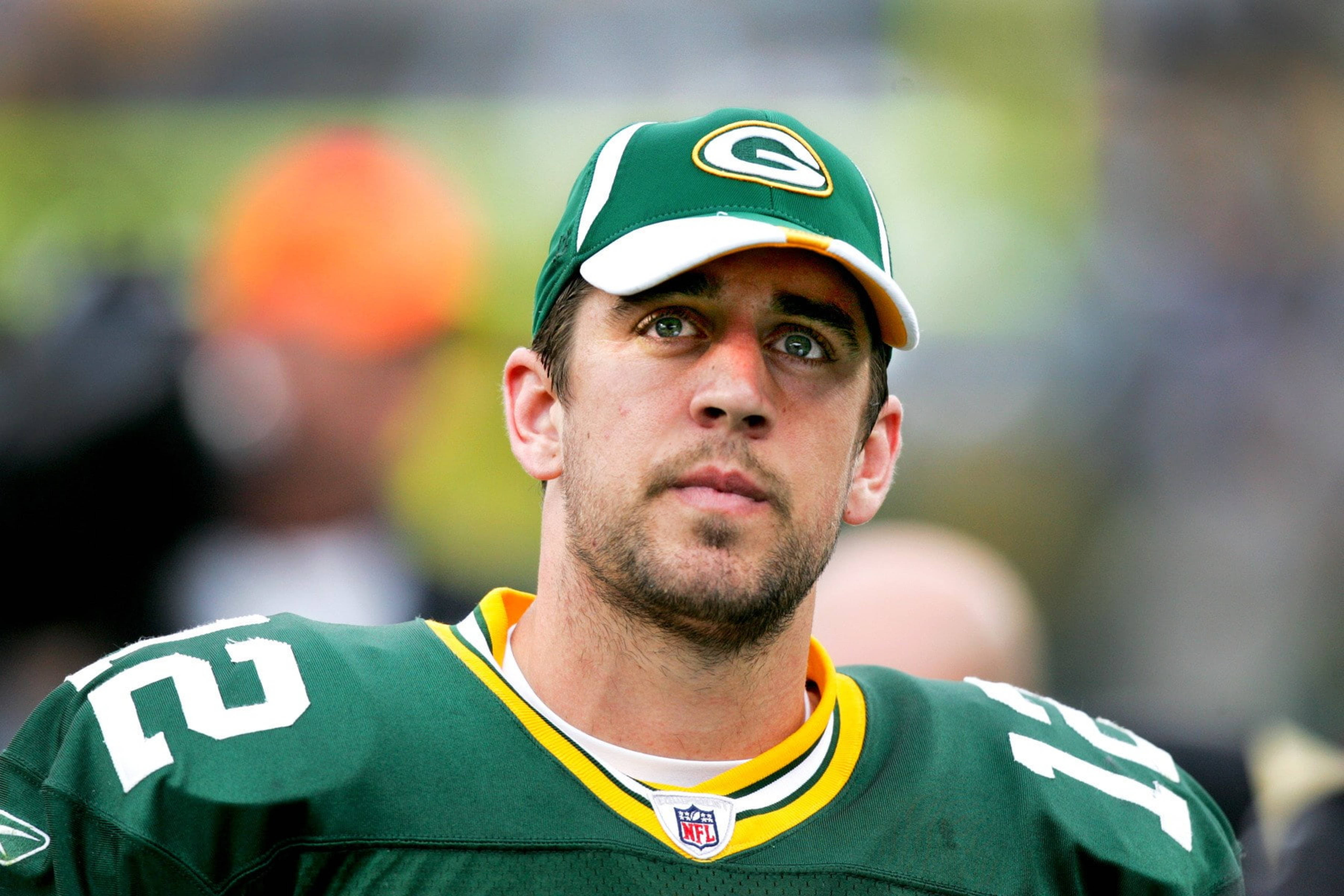 Aaron Rodgers 桌布 壁紙 — 綠灣包裝工美式足球員身穿綠色球衣和帽子，專注地向前看的特寫。