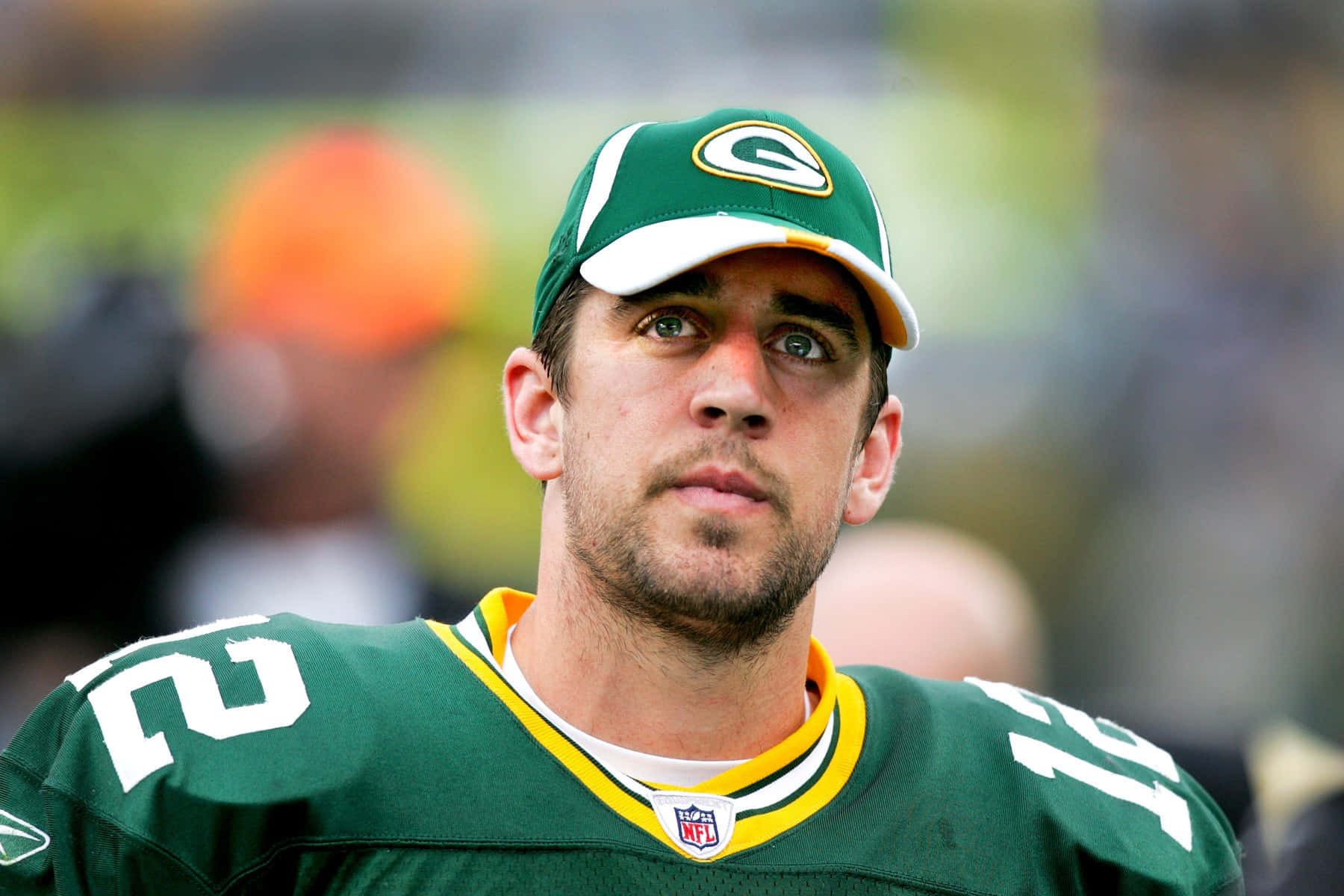 Aaron Rodgers 桌布 壁紙 — 綠灣包裝工美式足球員身穿綠色球衣和帽子，專注地向前看的特寫。