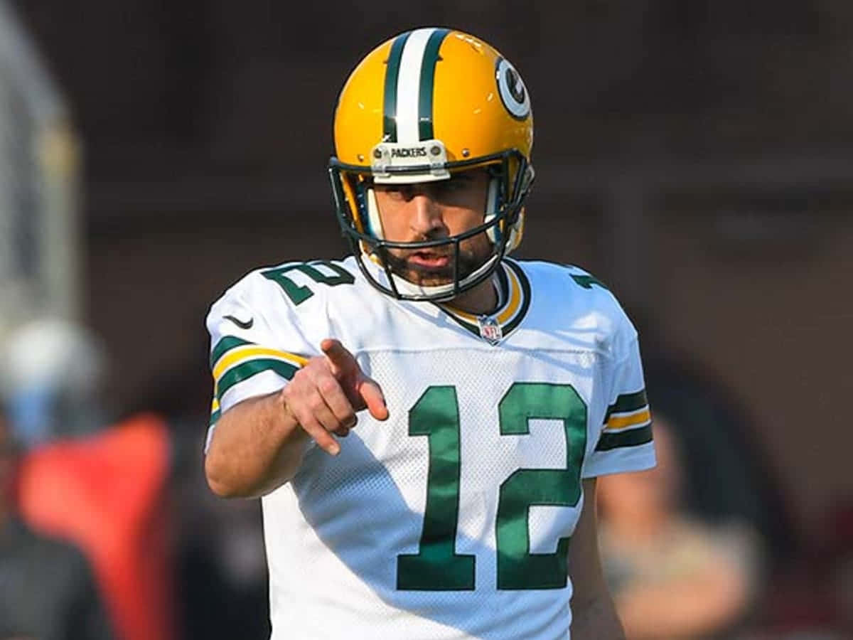 NFL 桌布 壁紙 — 綠灣包裝工隊的四分衛身穿白色和綠色制服，在日間美式足球比賽中專注地向前指點。
