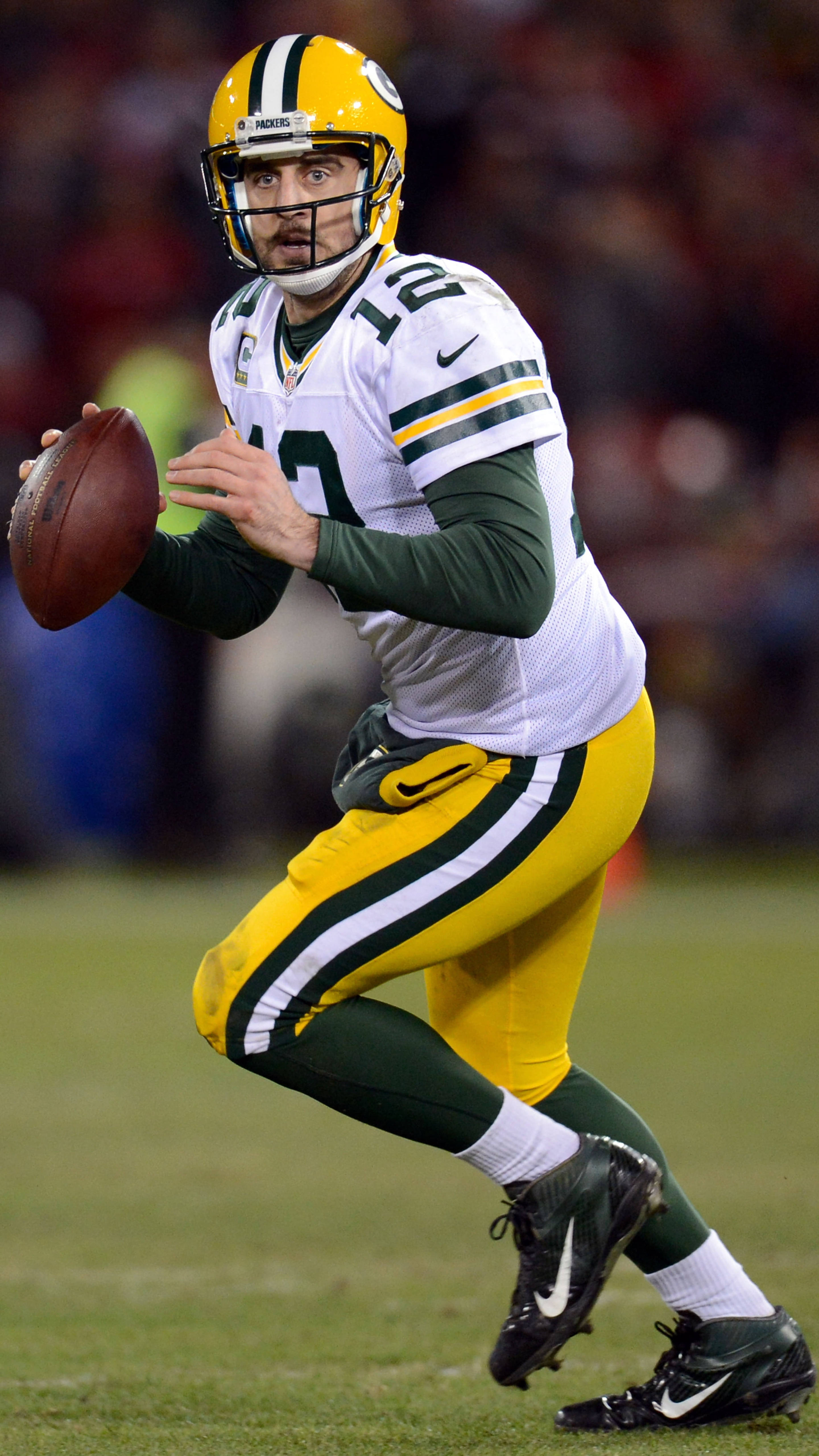 Aaron Rodgers 桌布 壁紙 — 綠灣包裝工隊的四分衛身穿綠色和金色制服，準備在夜間比賽中擲出橄欖球。
