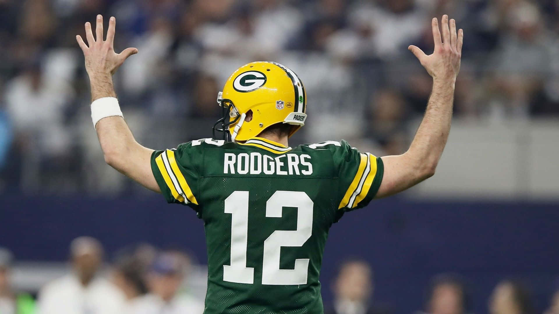 Aaron Rodgers 桌布 壁紙 — 綠灣包裝工隊的四分衛身穿綠色和金色12號球衣，在足球場上高舉雙臂慶祝。