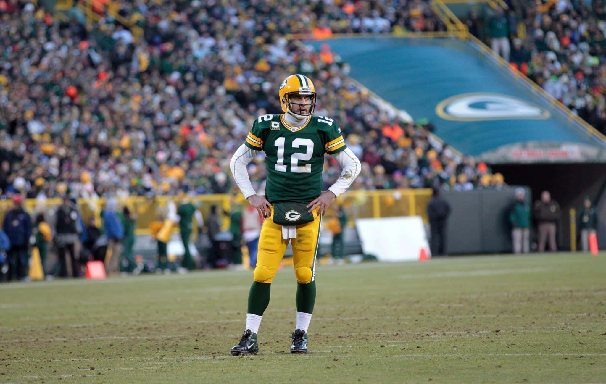 Aaron Rodgers 桌布 壁紙 — 綠灣包裝工隊的四分衛身穿綠金相間的球衣，在比賽中雙手叉腰站在場上。
