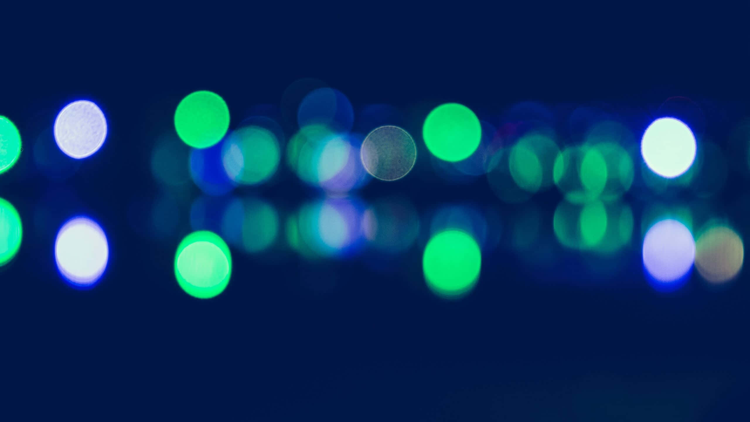 Light Effect 桌布 壁紙 — 綠色、藍色和白色的散景燈光在深海軍藍背景上柔和地發光，營造出夢幻般的抽象夜景。