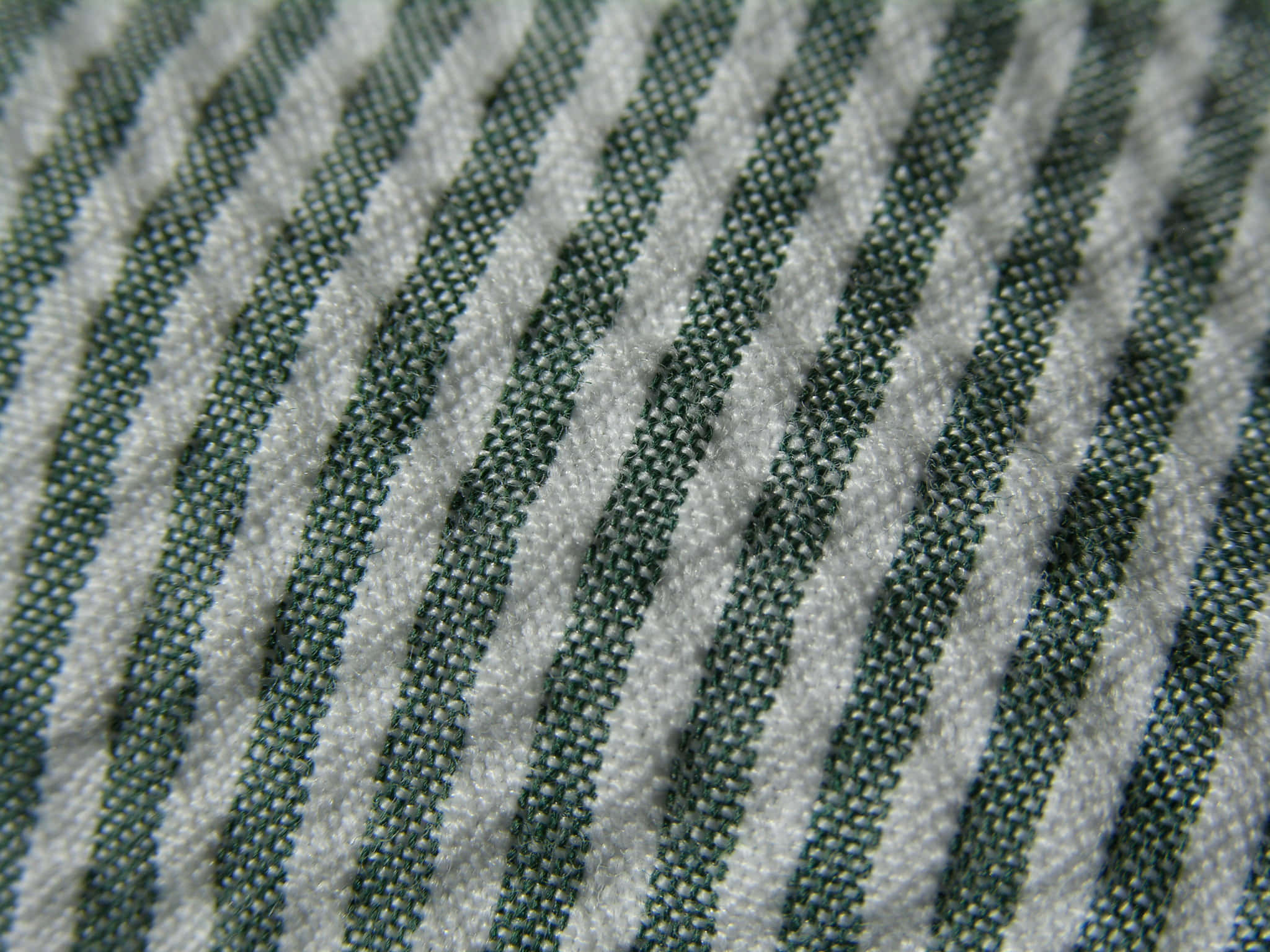 Textured 桌布 壁紙 — 綠色和白色斜紋布料的特寫，顯示出有紋理的編織和柔軟的摺痕。
