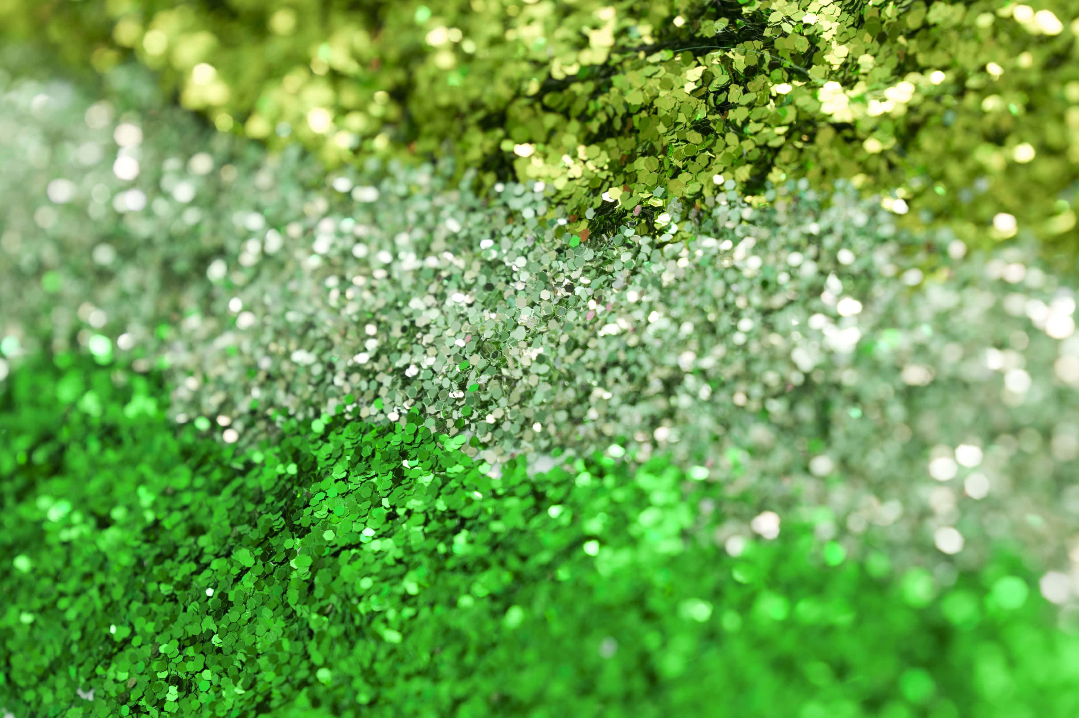 Green Glitter 桌布 壁紙 — 綠色和銀色亮粉層疊的特寫，營造出帶有柔和散景效果的閃亮紋理背景。