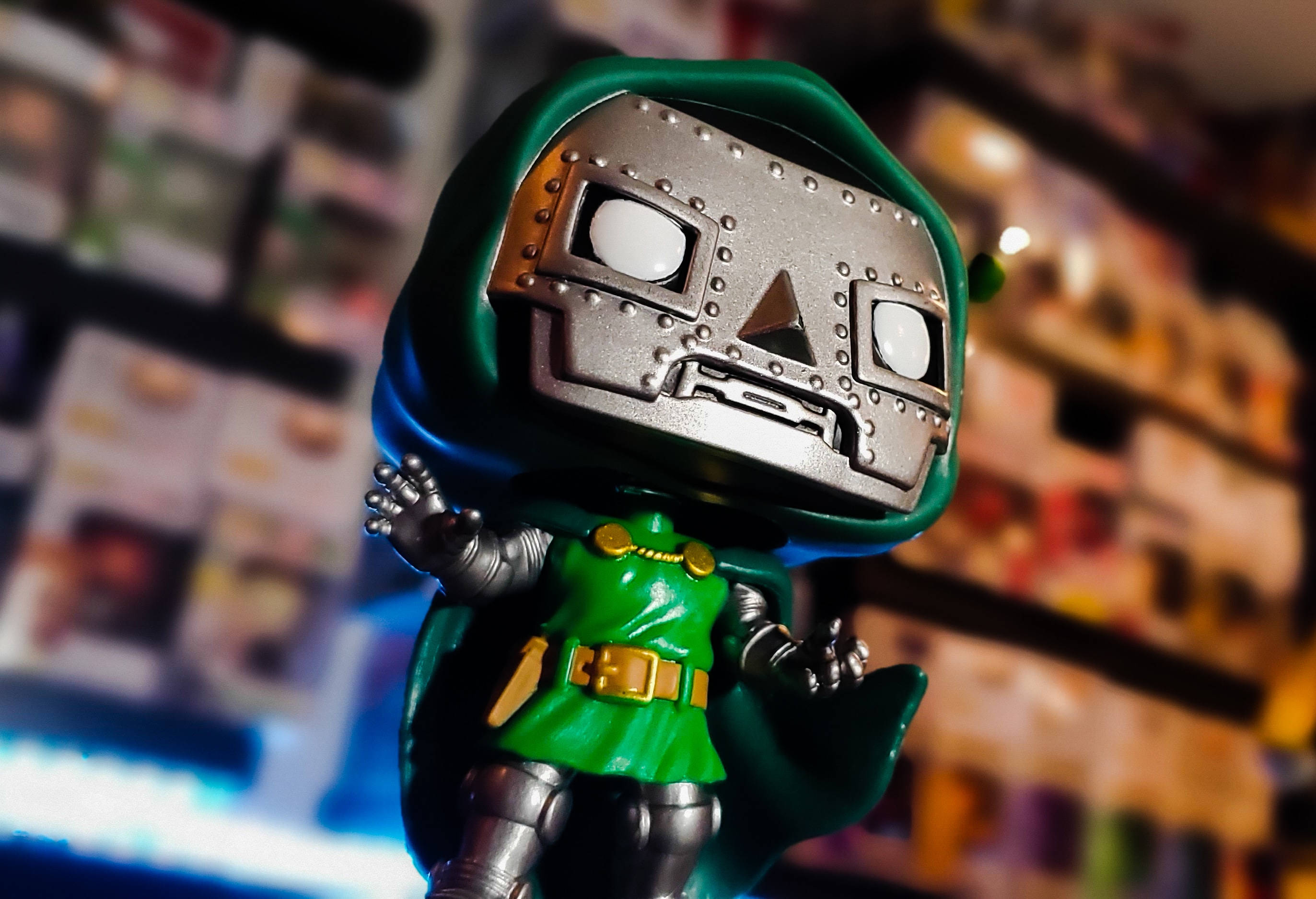 Doctor Doom 桌布 壁紙 — 綠色和銀色的毀滅博士 Funko Pop 人偶特寫，背景是模糊的收藏盒。