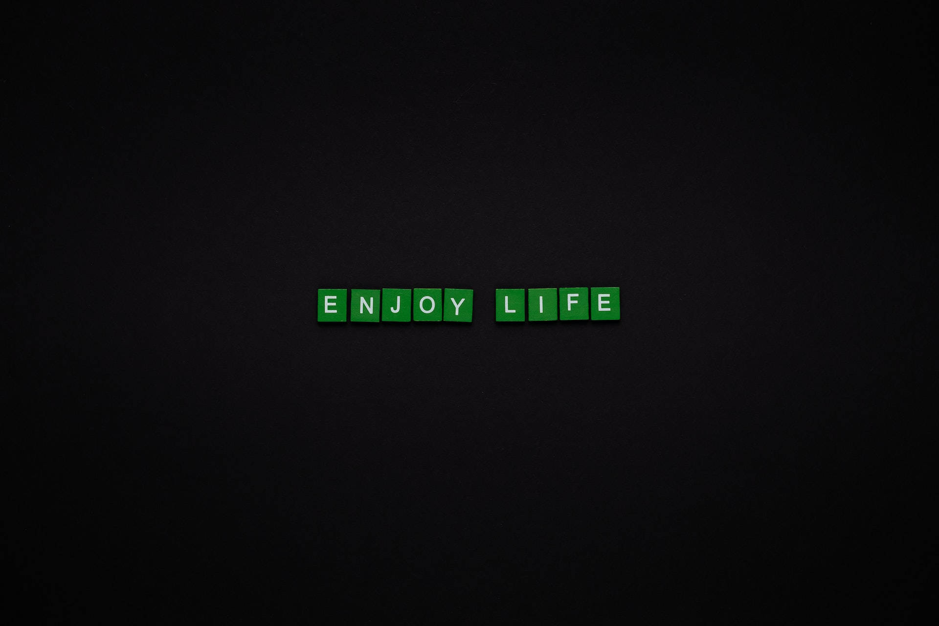 黑色 桌布 壁紙 — 綠色字母瓷磚在深色紋理背景中央拼出enjoy life。