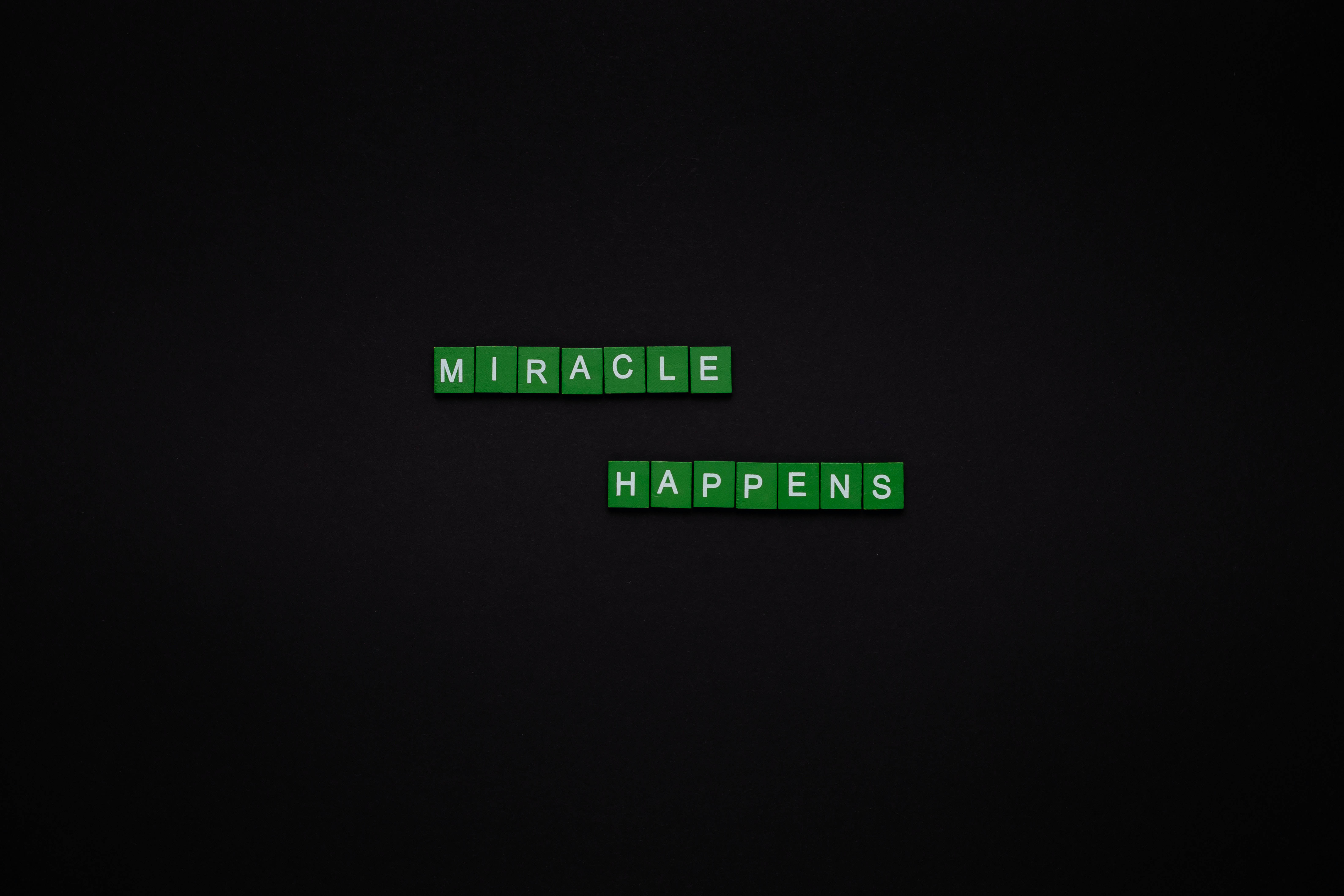 Screen 桌布 壁紙 — 綠色字母瓷磚在深色紋理背景中央拼出「MIRACLE HAPPENS」。