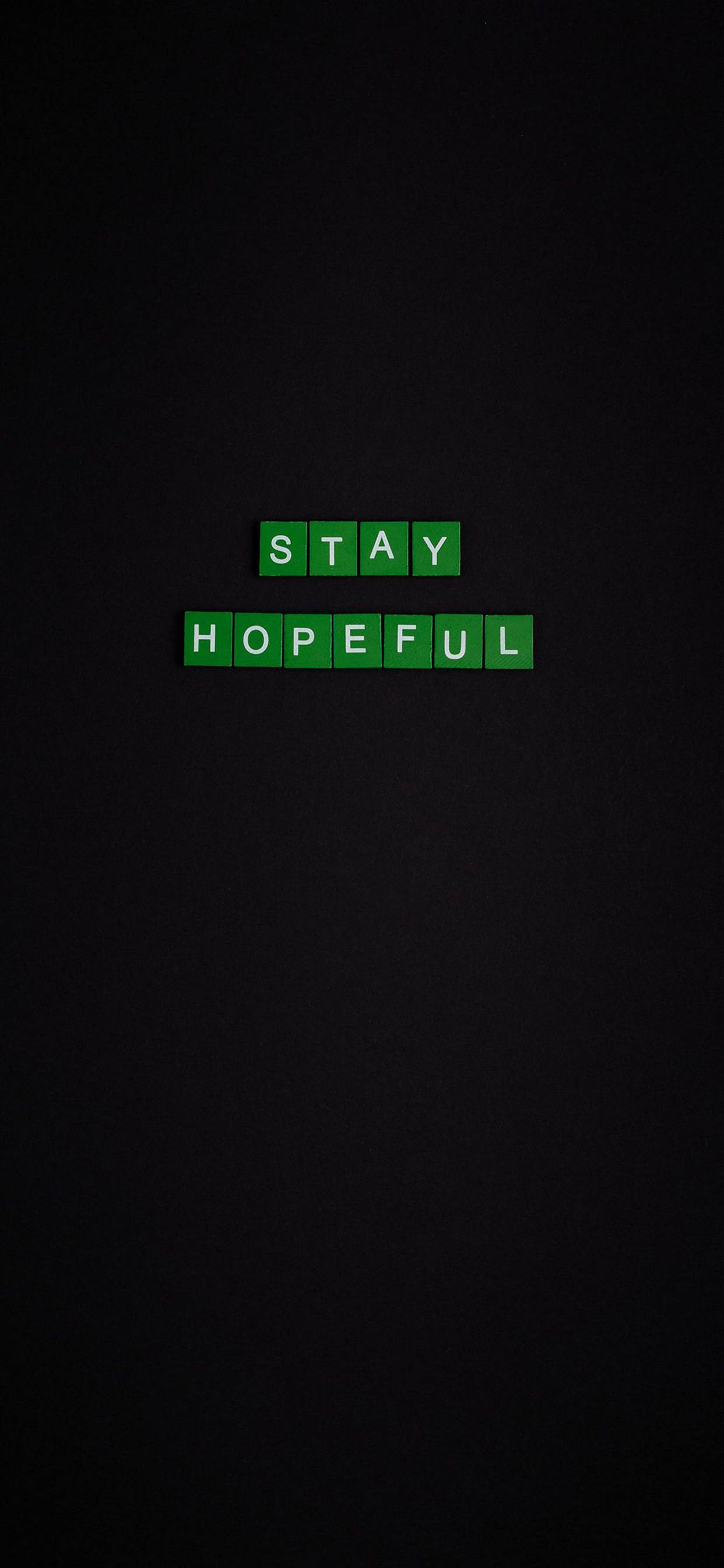 勵志 iPhone 桌布 壁紙 — 綠色拼字磚塊拼出 stay hopeful，居中放置在深色紋理背景上。