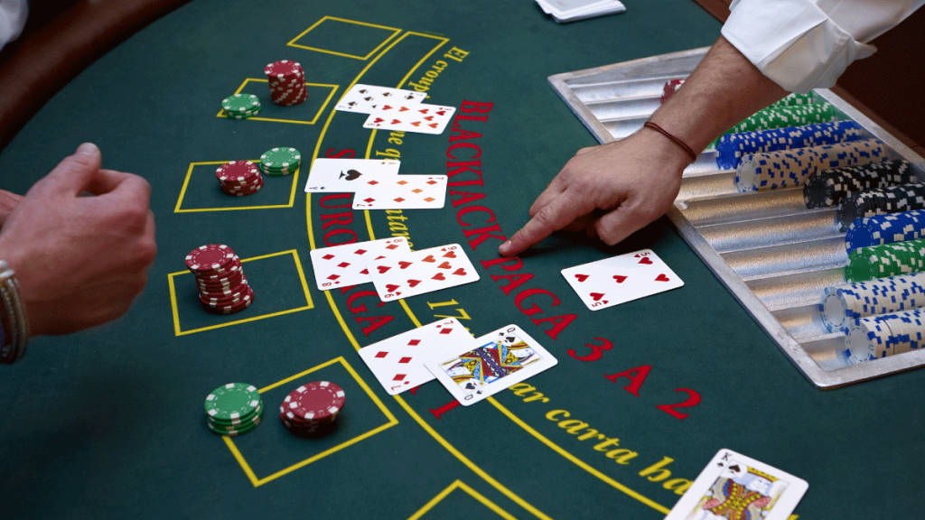 Casino 桌布 壁紙 — 綠色氈面賭桌上玩二十一點的手部特寫，散落著紙牌和彩色籌碼。