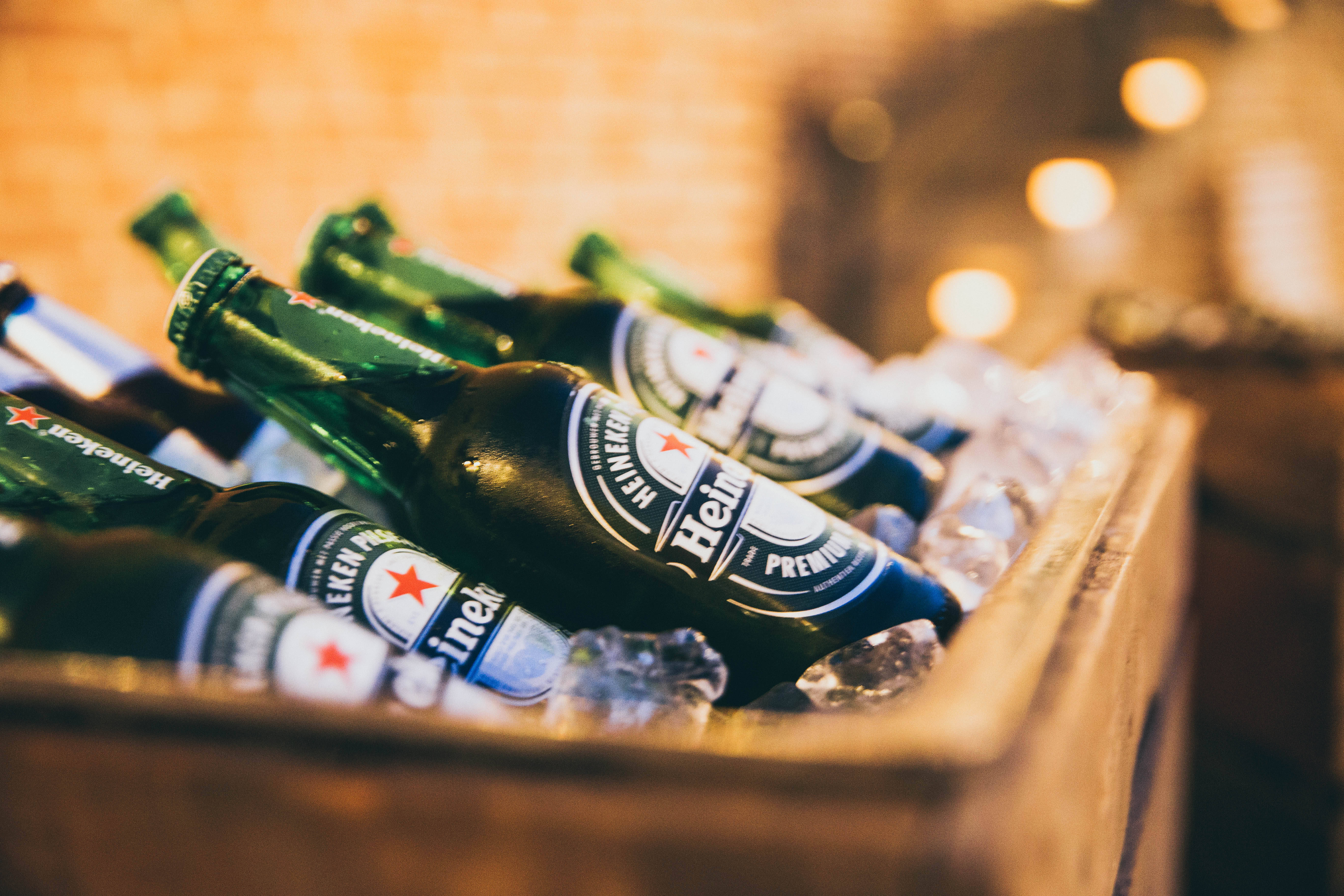 Beer 桌布 壁紙 — 綠色海尼根啤酒瓶放在木箱內的冰塊中，在溫暖的環境燈光下。