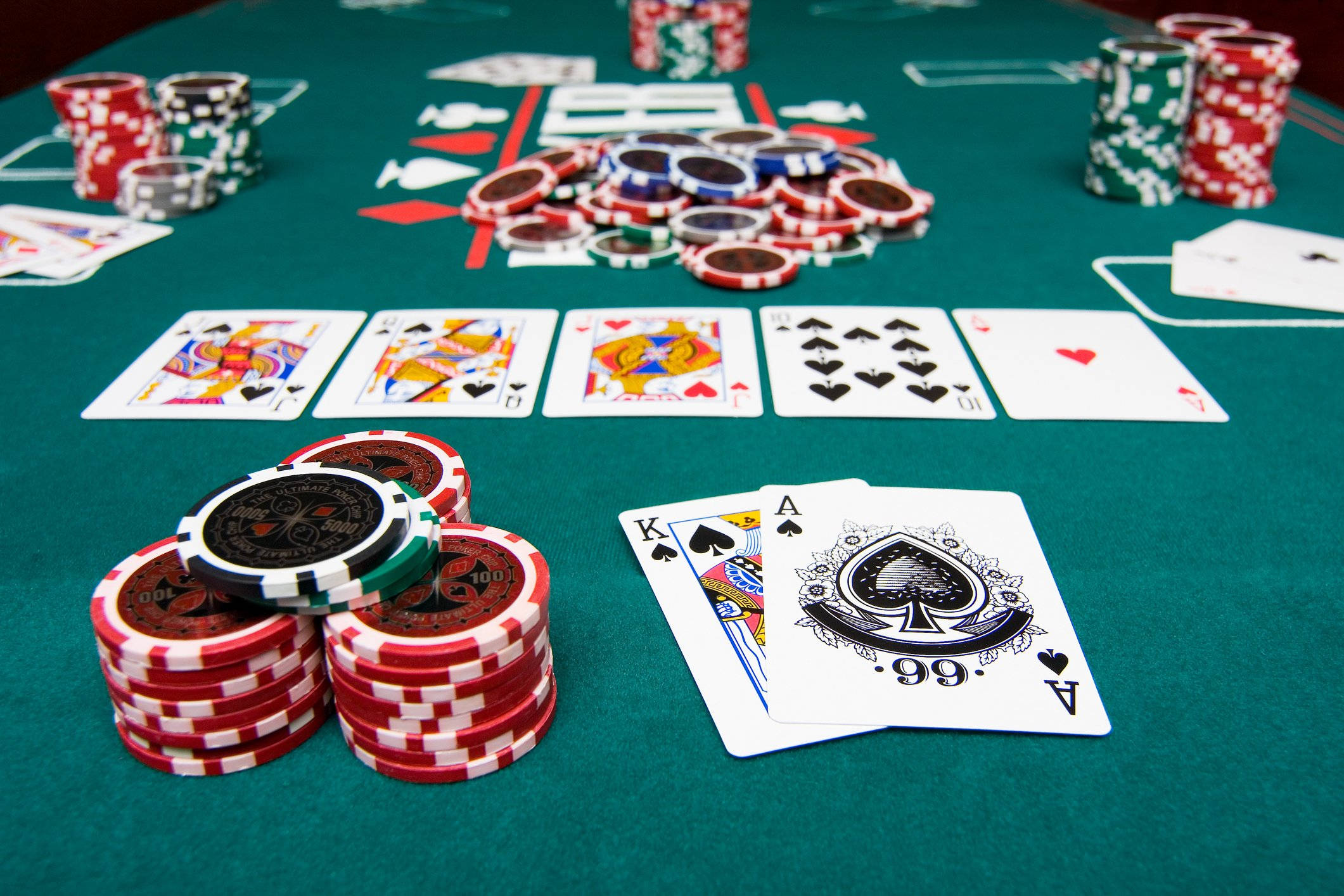 Casino 桌布 壁紙 — 綠色賭桌近景，散落著撲克牌和一堆堆色彩繽紛的賭場籌碼。