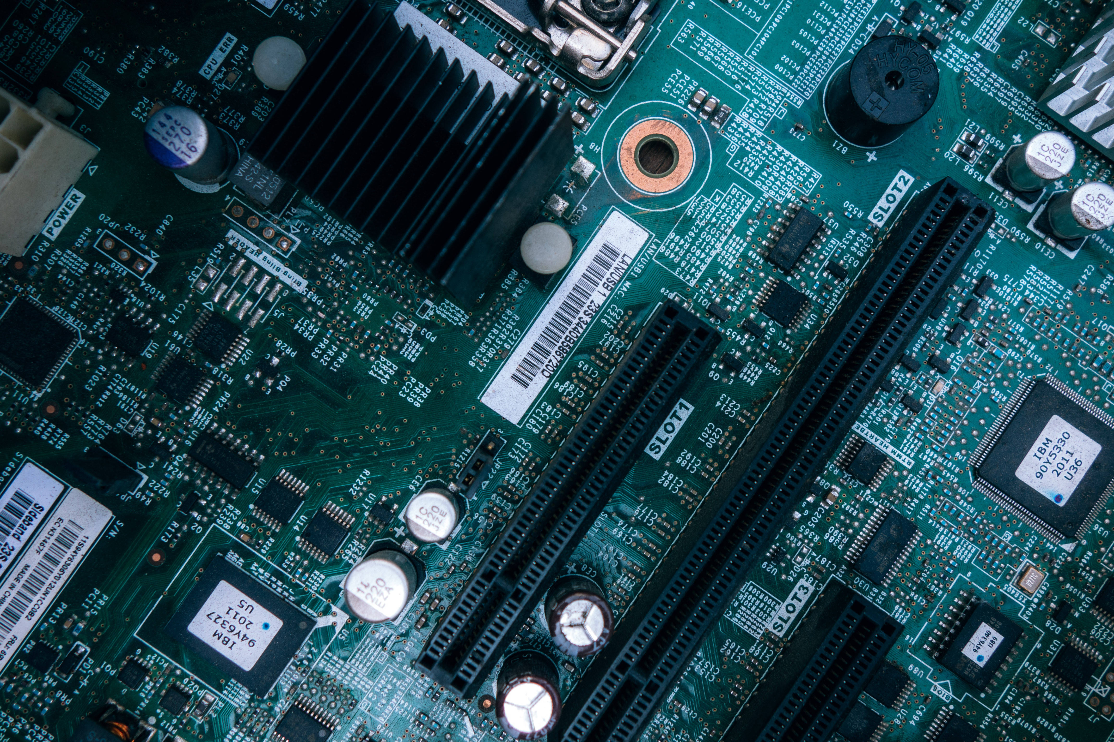 Motherboard 桌布 壁紙 — 綠色電腦主機板的詳細特寫，在明亮燈光下展示複雜的電路和組件。